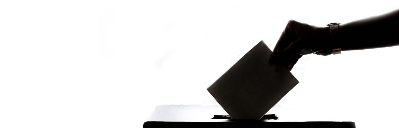 Symbolbild Wahlurne mit Hand und Wahlzettel
