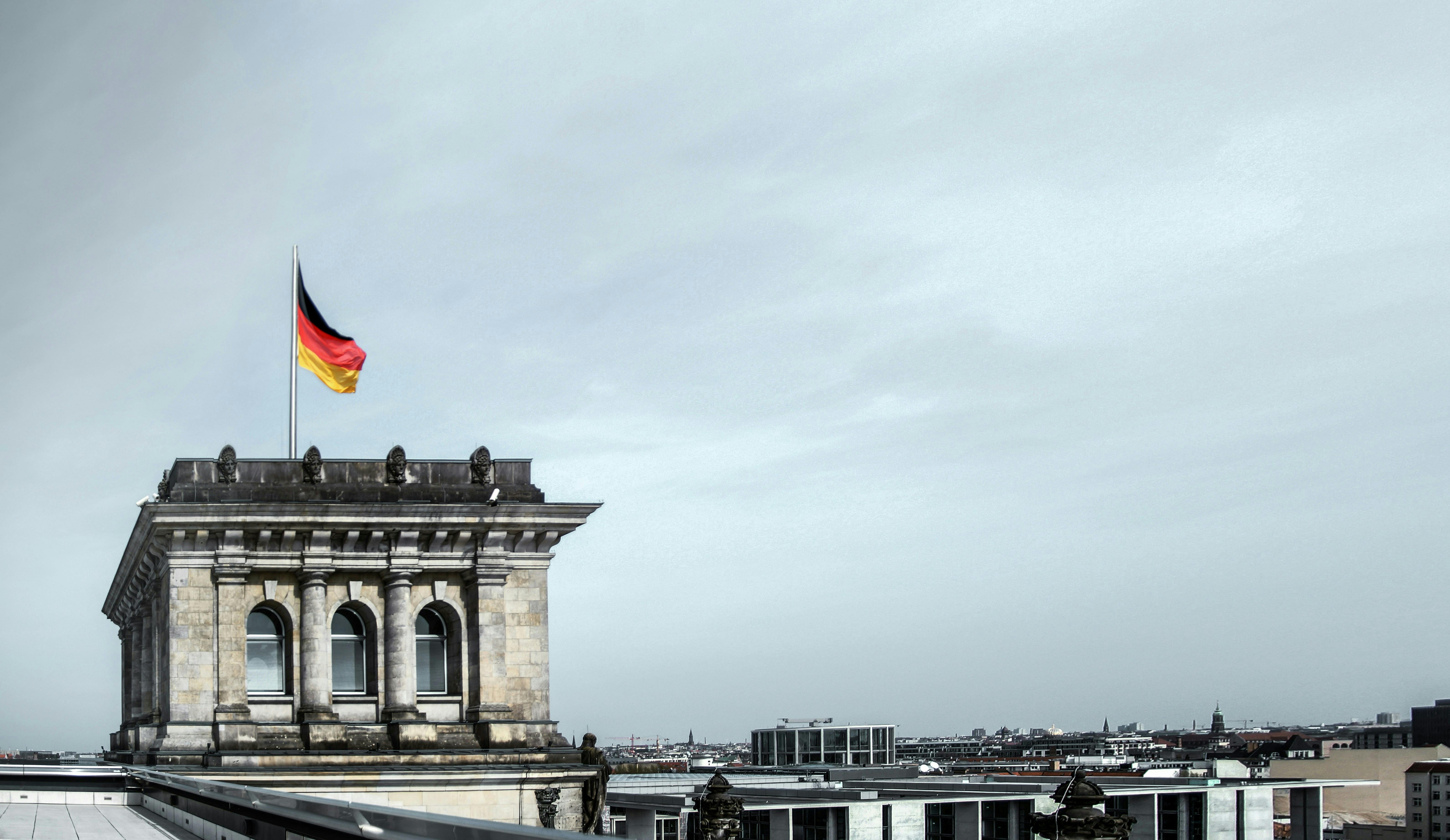 Blick auf den Reichstag mit deutscher Fahne im Wind und bewölktem Himmel