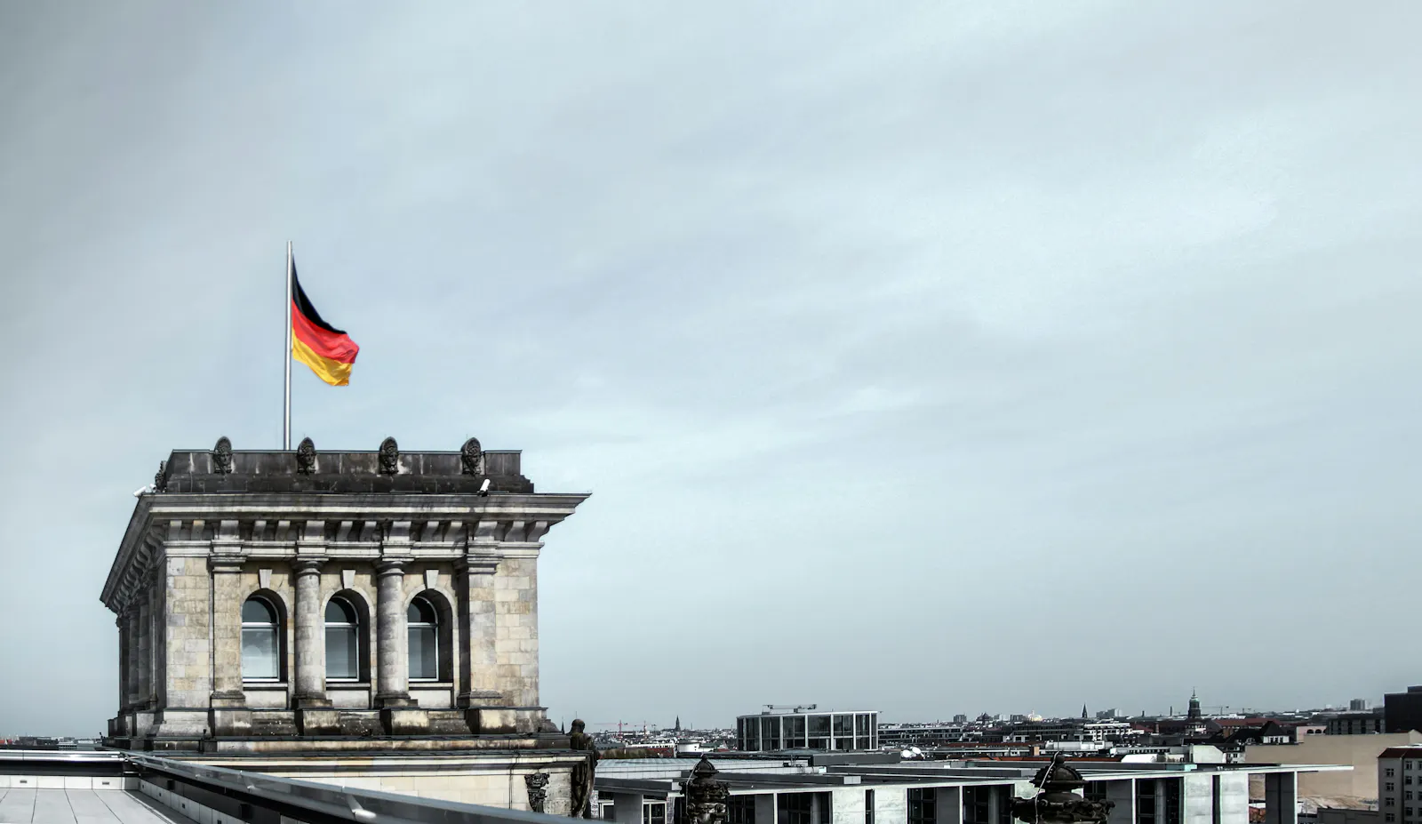 Blick auf den Reichstag mit deutscher Fahne im Wind und bewölktem Himmel