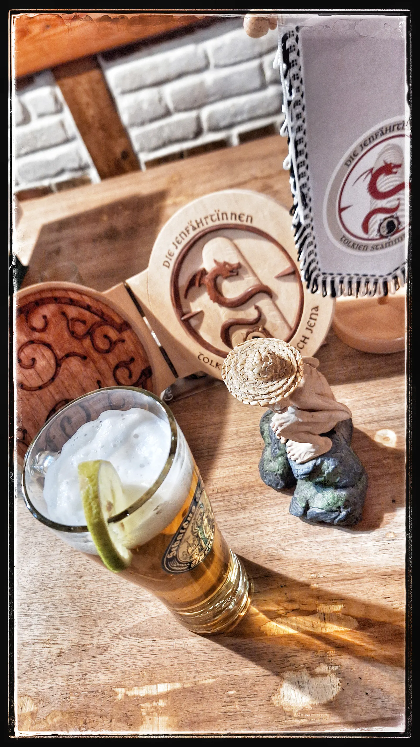 Photo from pub in Jena called Alster, depicting a beer, a hand-crafted hobbit hole door, Smiguel and the the Tolkien regulars' table crest