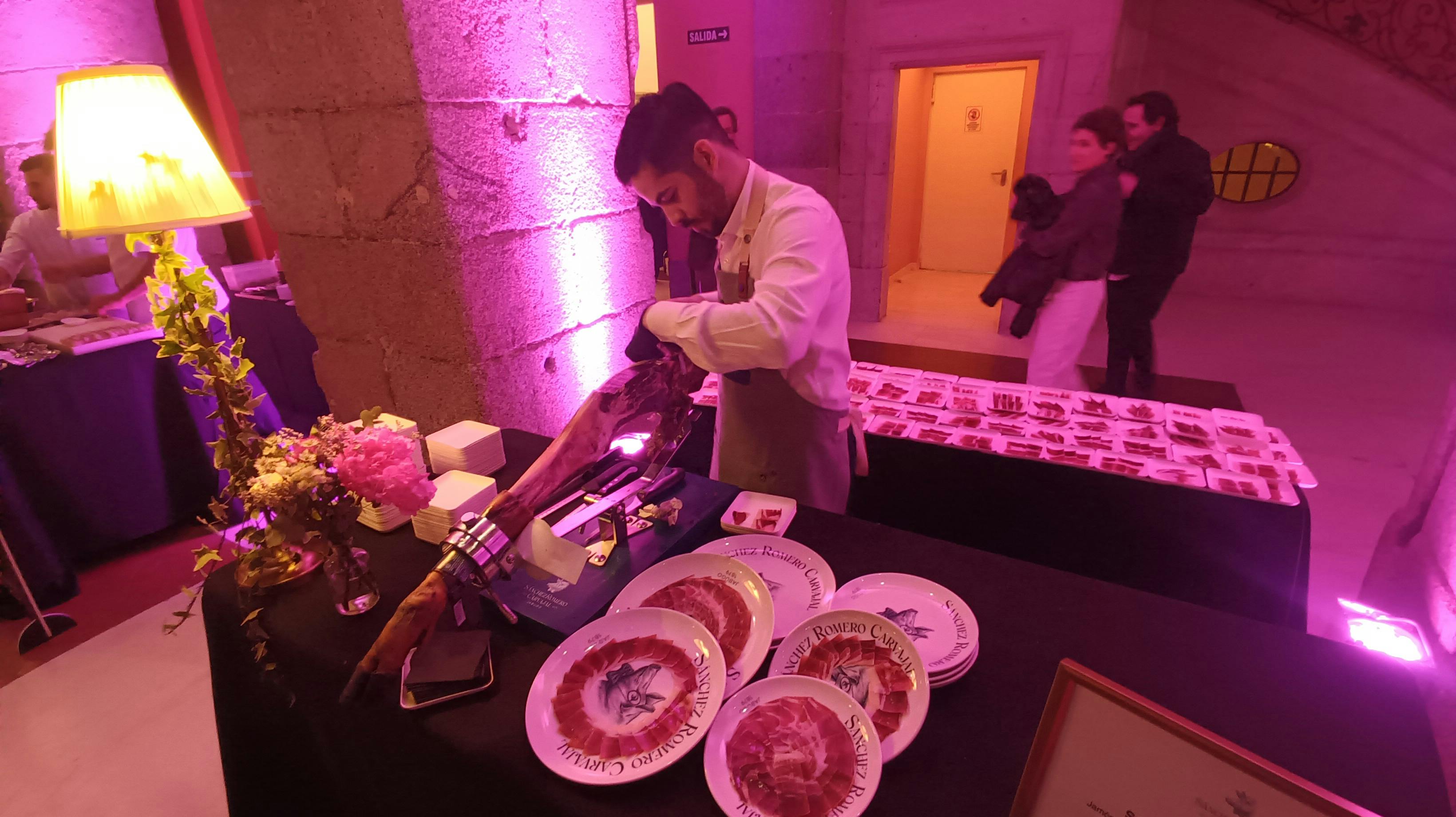 Auf der Eröffnung des Madrider Gastro-Festival Madrid Fusion schneidet ein Schinkenschneider konzentriert einen iberischen Schinken auf. Um ihn herum stehen Teller mit bereits aufgeschnittenem Schinken.