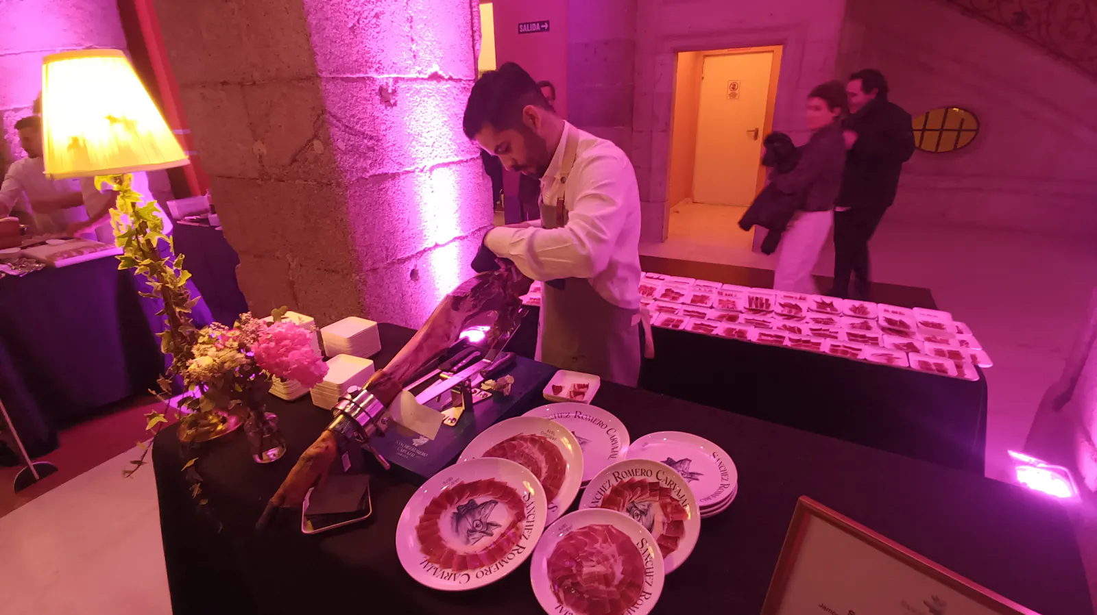 Auf der Eröffnung des Madrider Gastro-Festival Madrid Fusion schneidet ein Schinkenschneider konzentriert einen iberischen Schinken auf. Um ihn herum stehen Teller mit bereits aufgeschnittenem Schinken.