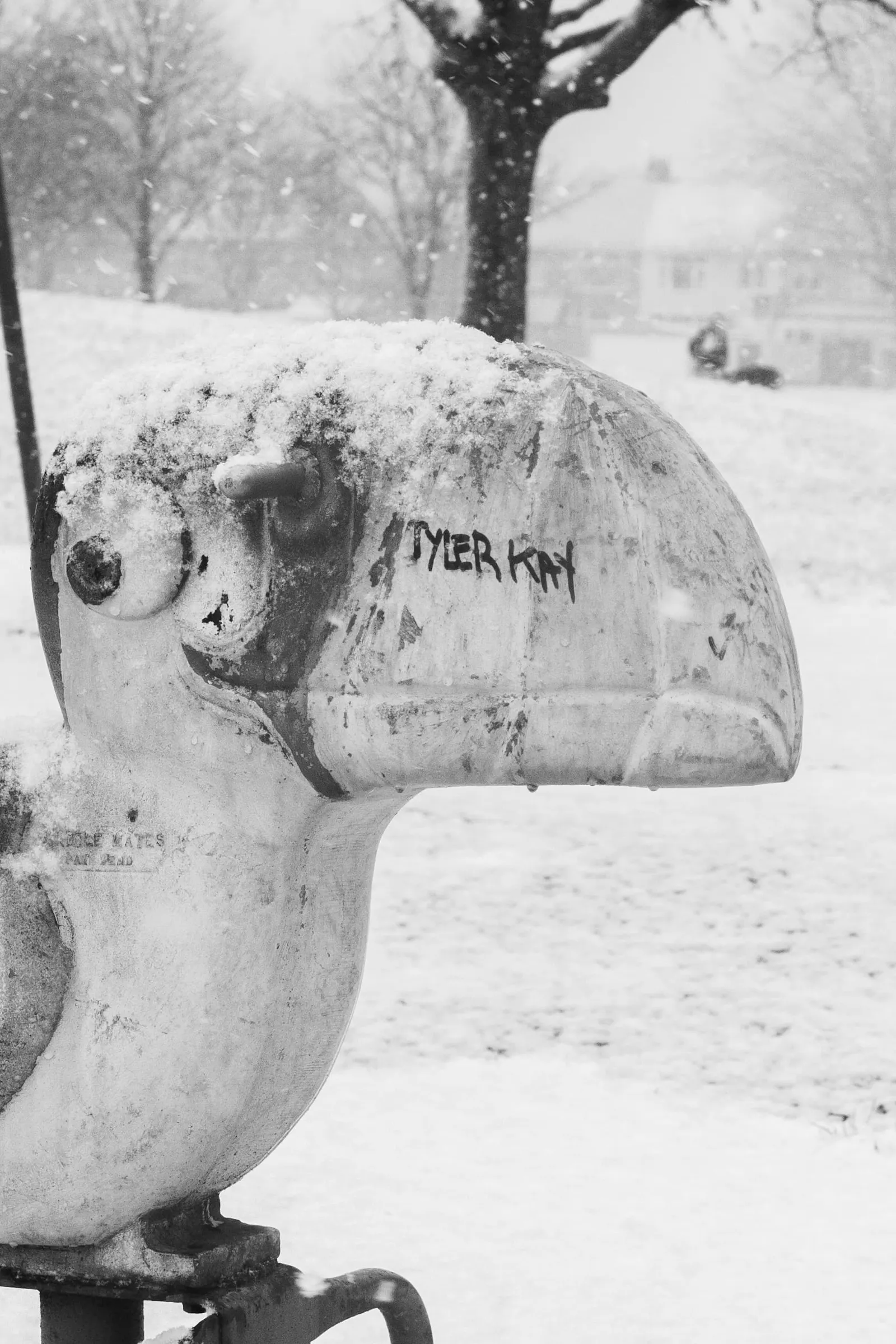 A playground toy is covered with snow and a graffiti tag