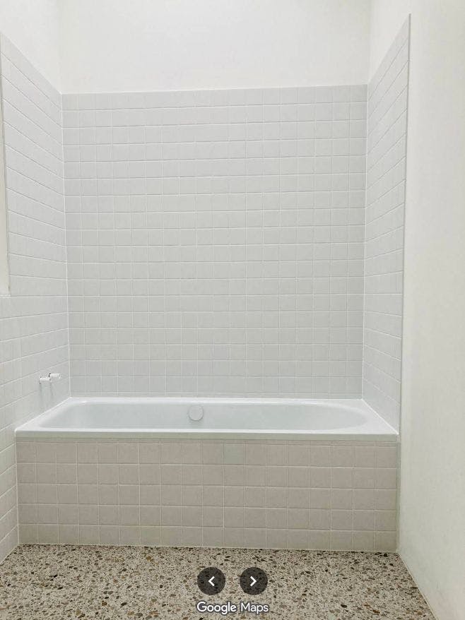 Foto Badezimmer mit Badewanne; Boden mit beige-braunen Terrazzo-Fliesen, Wände mit naturweißen, kleinformatigen Feinsteinfliesen;
Grafik ist verlinkt mit der original Google-Rezension