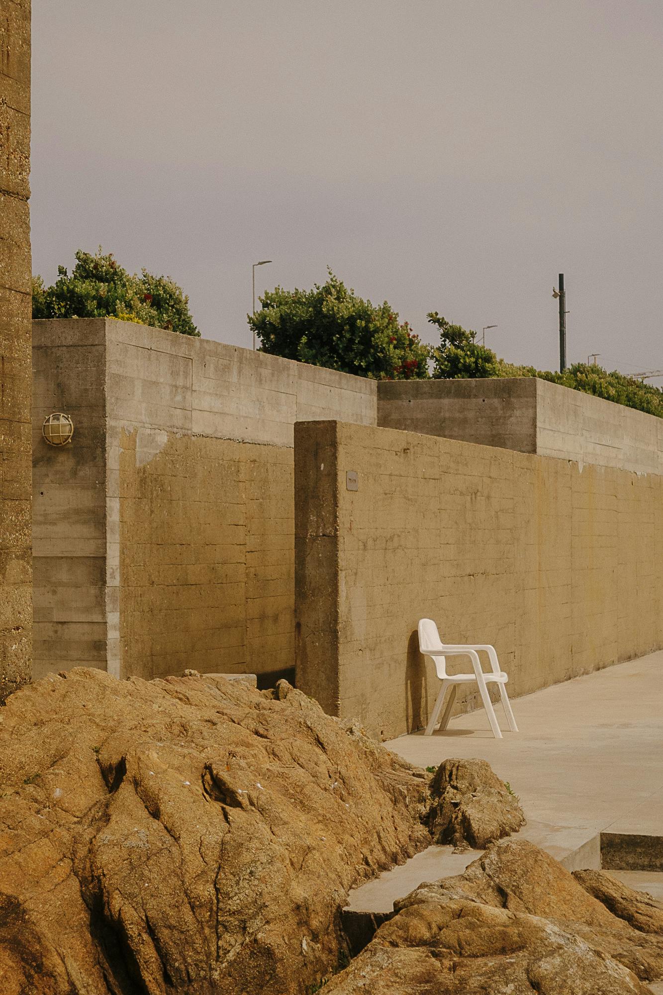 Ein Plastikstuhl vor einer Betonwand im Piscina das Marés von Alvaro Sizar bei Porto.