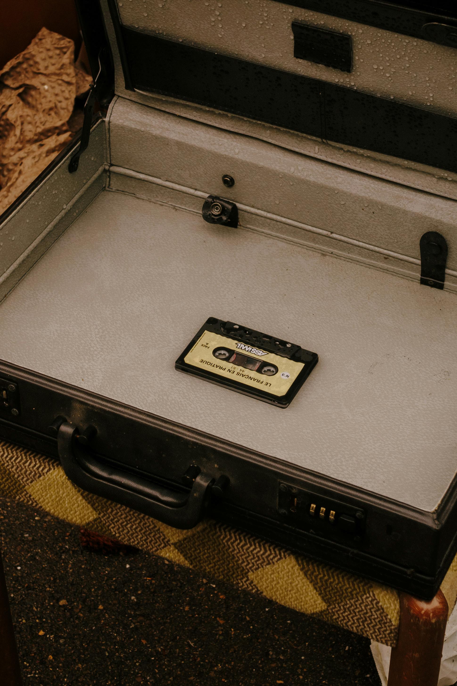 Kassette mittig in einem alten, aufgeklappten Aktenkoffer liegend.