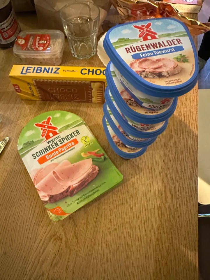 Ein Bild vom Tisch beim Januar-Dreh mit einem Stapel aus fünf Teewurst-Packungen. Daneben Kekse, Veganer Schicken Spicker, Fleischsalat und Kekse.