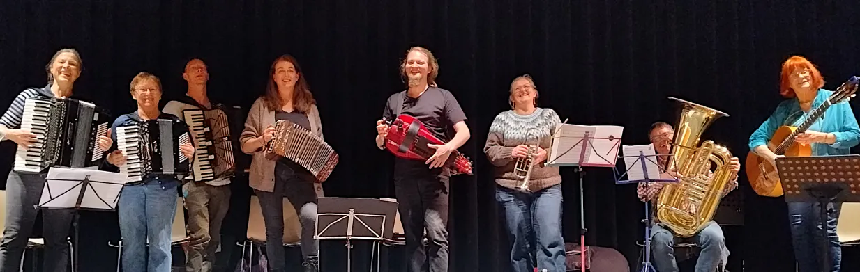 Acht Musiker_innen lachen in die Kamera