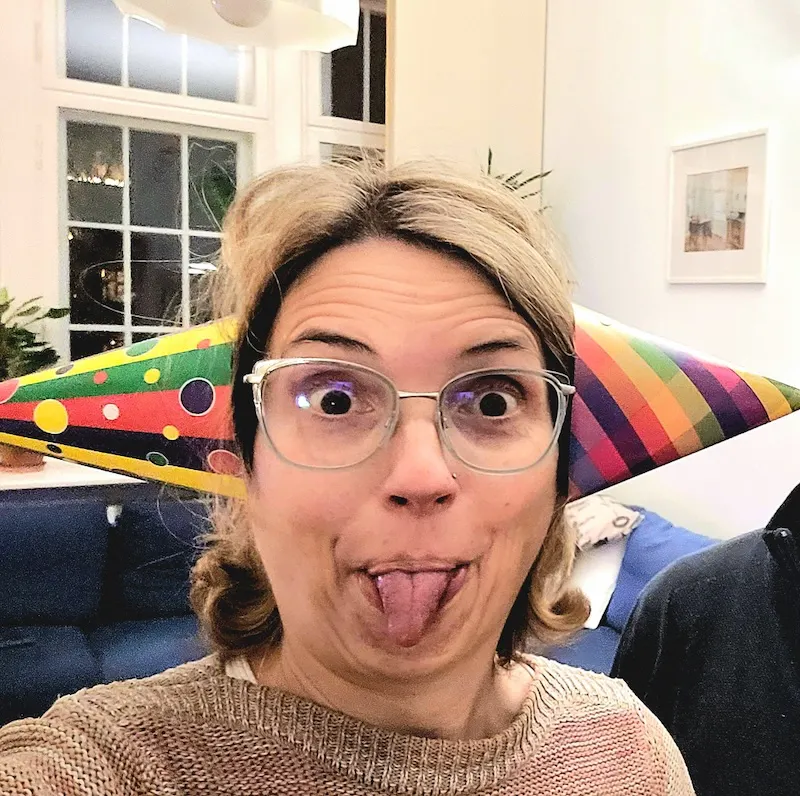 Christine Piontek streckt die Zunge raus und hat bunte Partyhütchen aus Pappe auf beiden Ohren.
