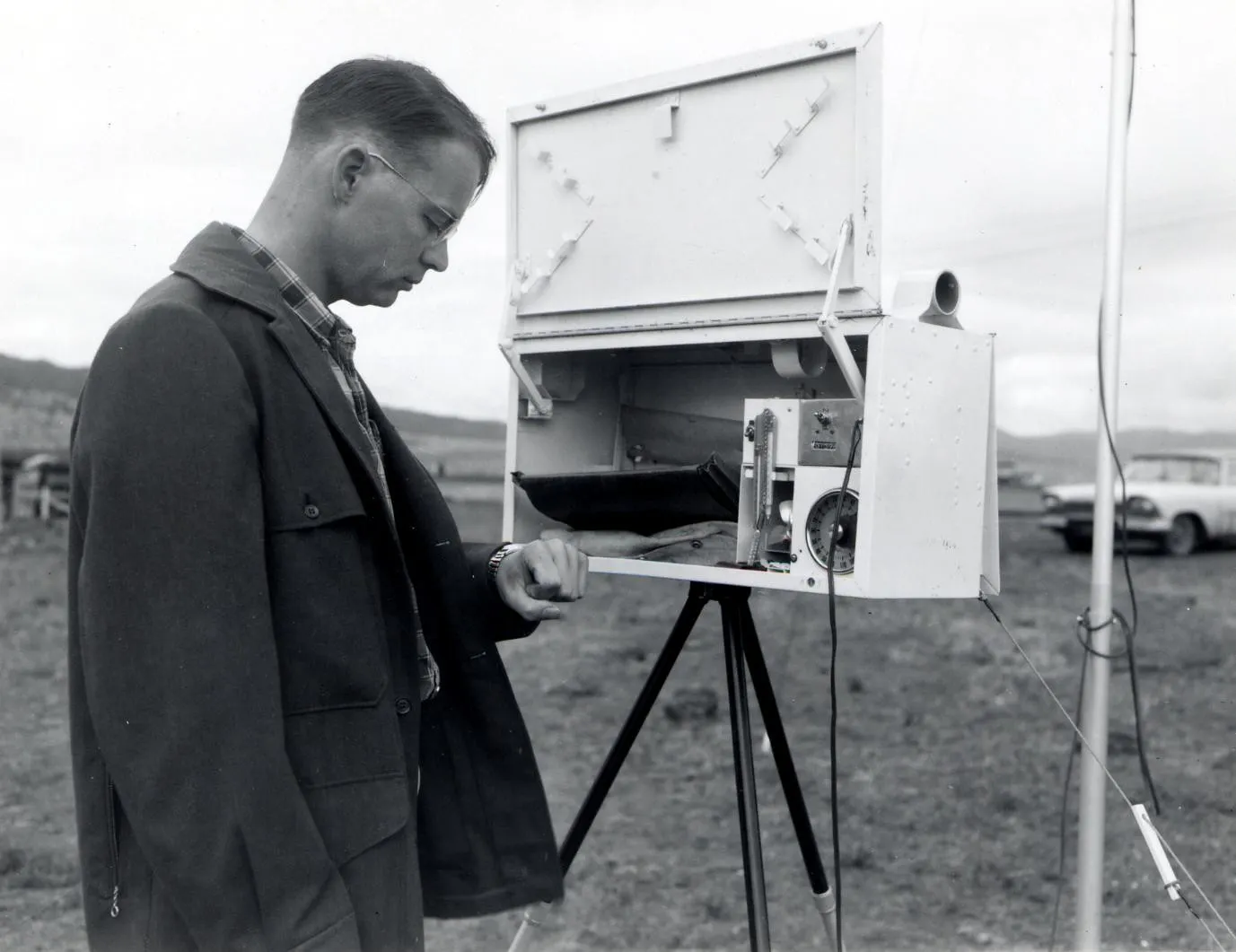 1958. Art McKee checks portable weather station. Spruce budworm control project. John Day airstrip, Oregon.