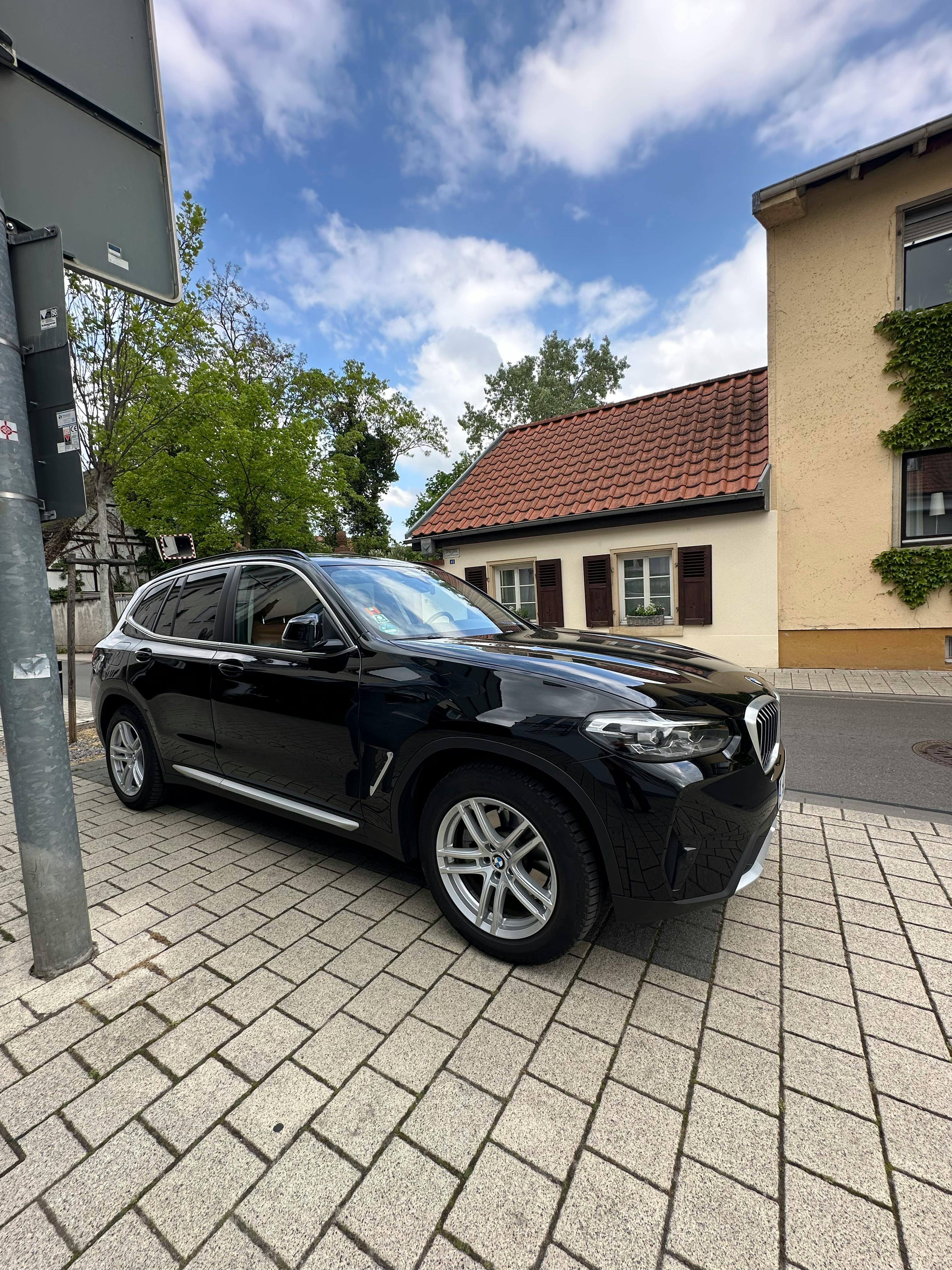 Großer schwarzer SUV, im Hintergrund ein mittelalterliches Haus, das kleiner ist als das geparkte Auto.