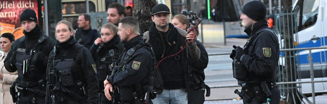 Bild zeigt verpixelte Polizistinnen und Polizisten und einen Mann mit Kamera