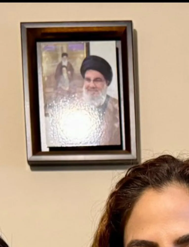 Screenshot eines von Shoura Hashemi geteilten Bildes auf X: Im Hintergrund hängen an der Wand Porträts von Hassan Nasrallah (Hisbollah) und Ali Chamenei (Iran). Die politischen Bezüge des Bildes bleiben im ursprünglichen Post unkommentiert.