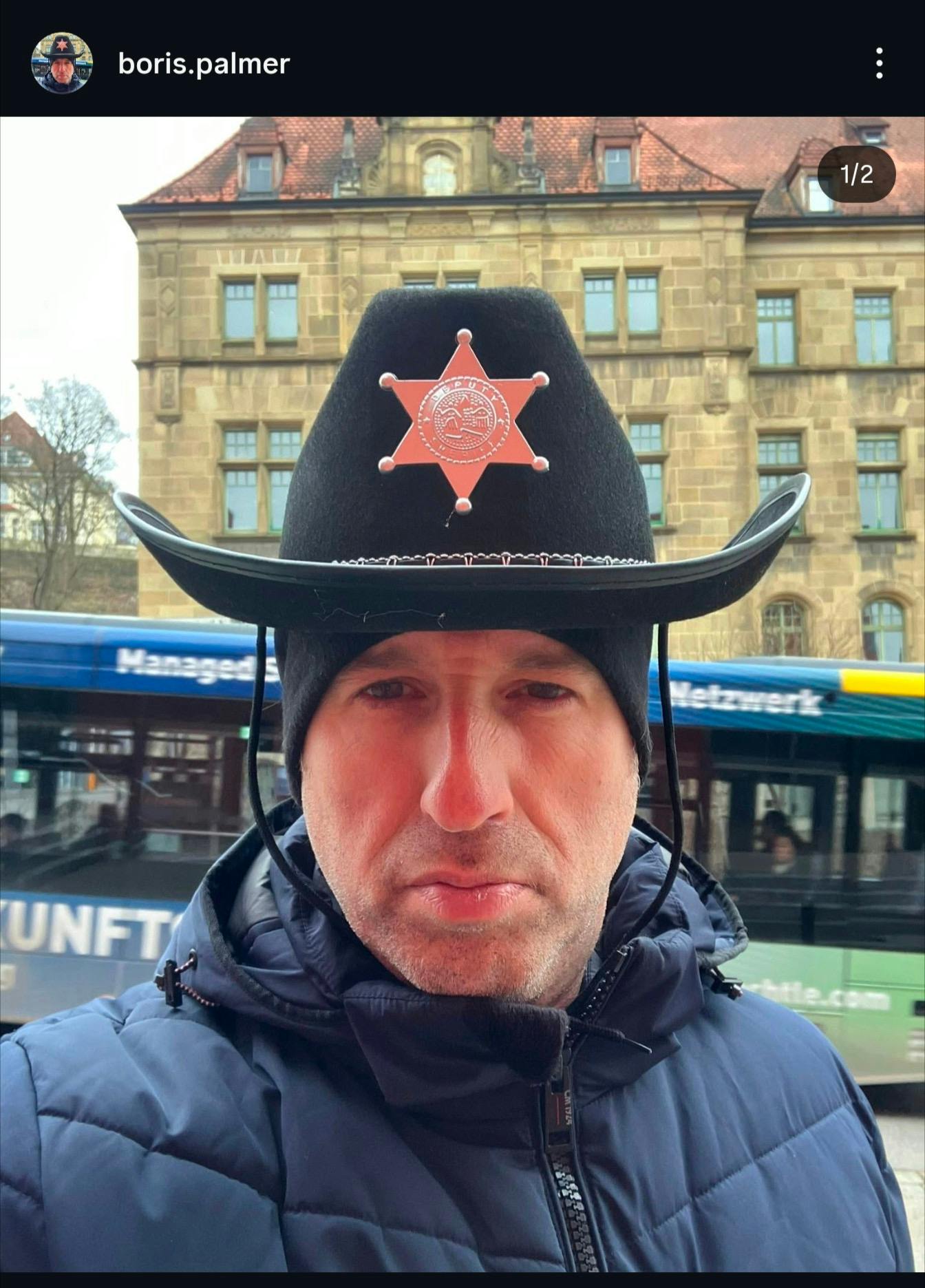 Boris Palmer trägt einen sherriffhut über seiner maschinell gestrickten Mütze und schaut ziemlich ausdruckslos in seine frontkamera