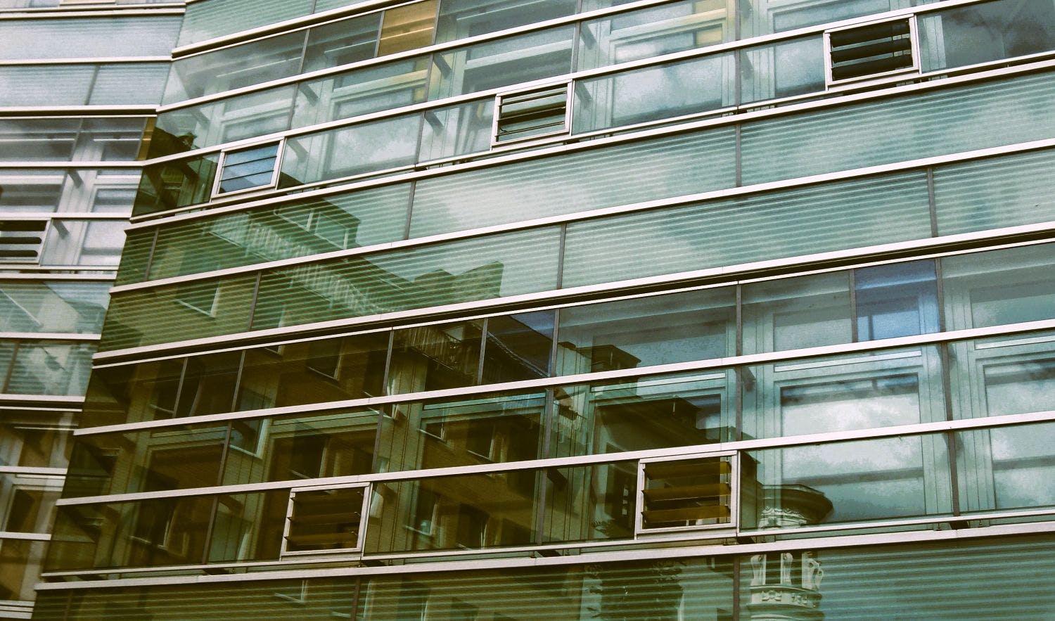 Wohnhäuser spiegeln sich in einem modernen Glasbau.