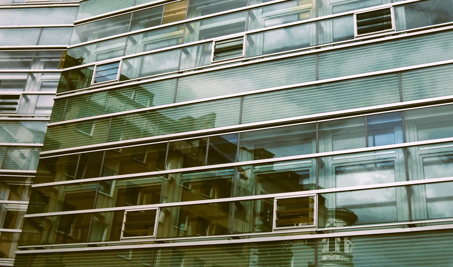 Wohnhäuser spiegeln sich in einem modernen Glasbau.