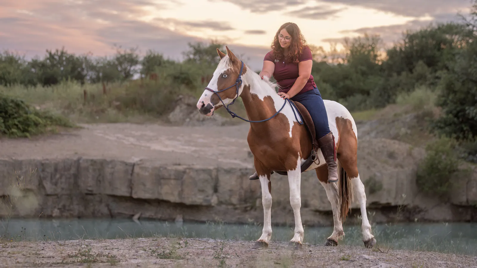 Aylin sitzt erhaben auf ihrem weiĂź-braunen Mustang. Im Hintergrund Felsen und karge Vegetation.