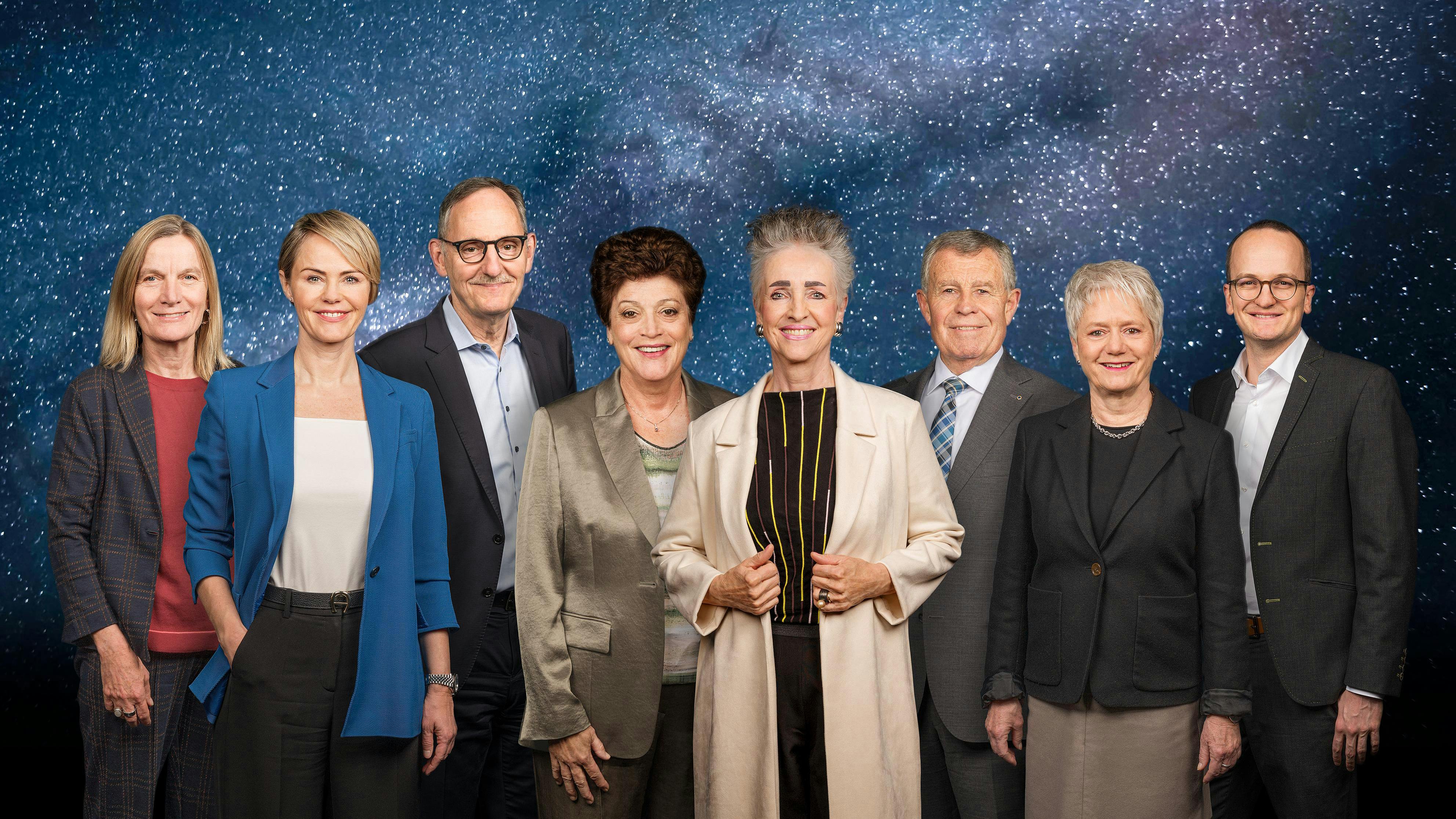 Zürcher Regierungsrat vor galaktischer Sternenkulisse; acht Mitglieder posieren als offizielle Gruppe für das Amtsjahr 2026/27.