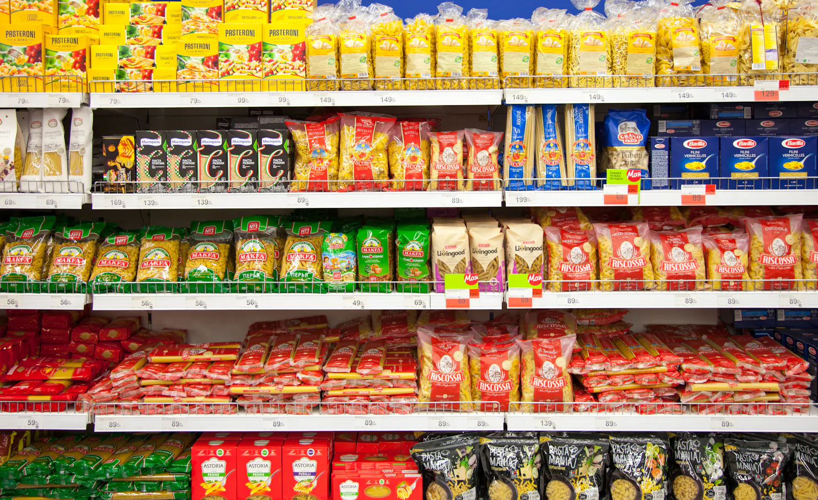 Das Bild zeigt gut gefüllte Regale in einem Supermarkt mit vielen verschiedenen Nudel-Packungen unterschiedlicher Marken.