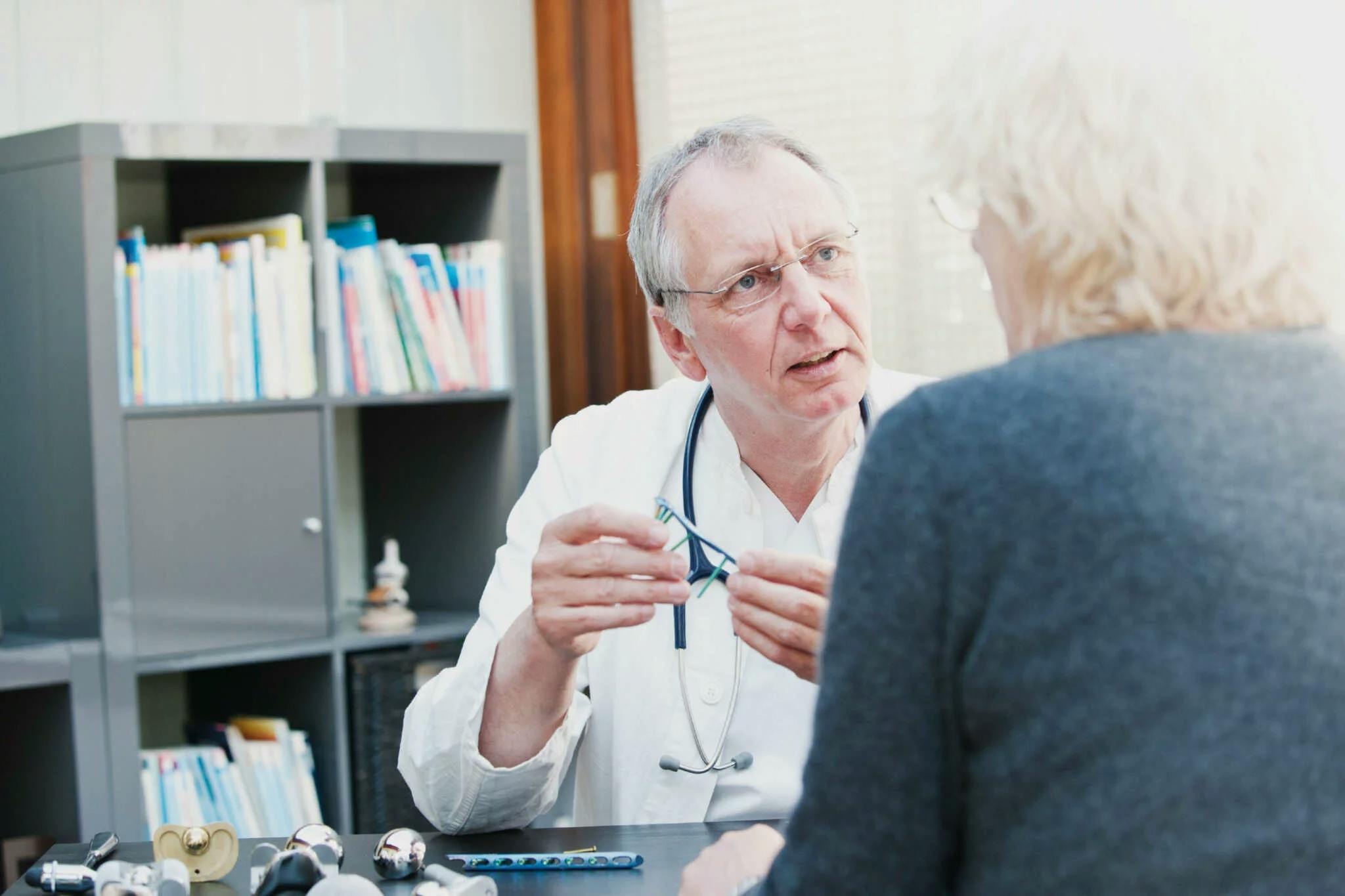 Arzt im mittleren Alter schaut seiner Patientin ins Gesicht, während er ihr etwas erklärt
