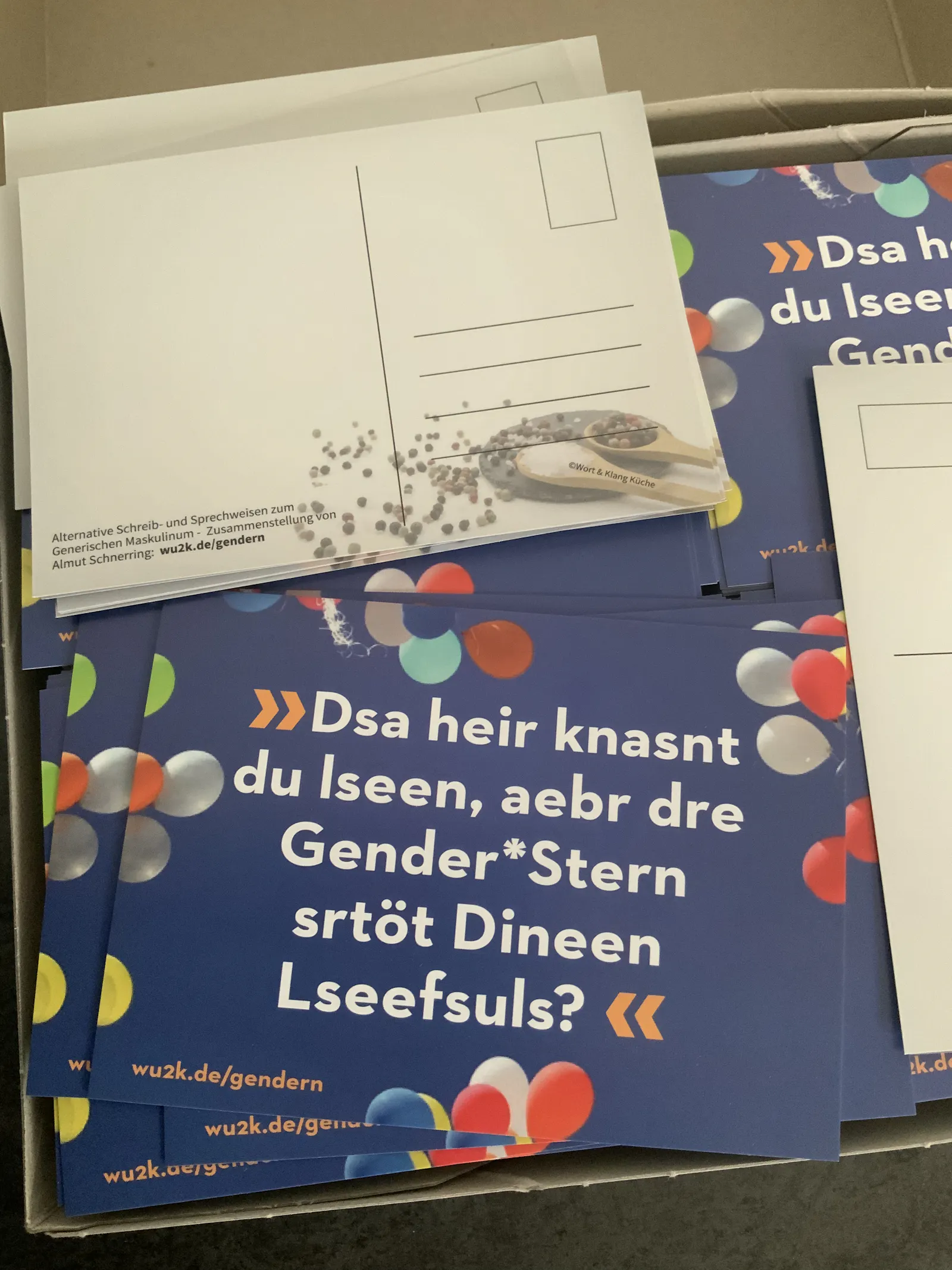 foto von einem Postkartenstapel, Vorderseite der Postkarte mit Text "Dsa heir knasnt du lseen?"