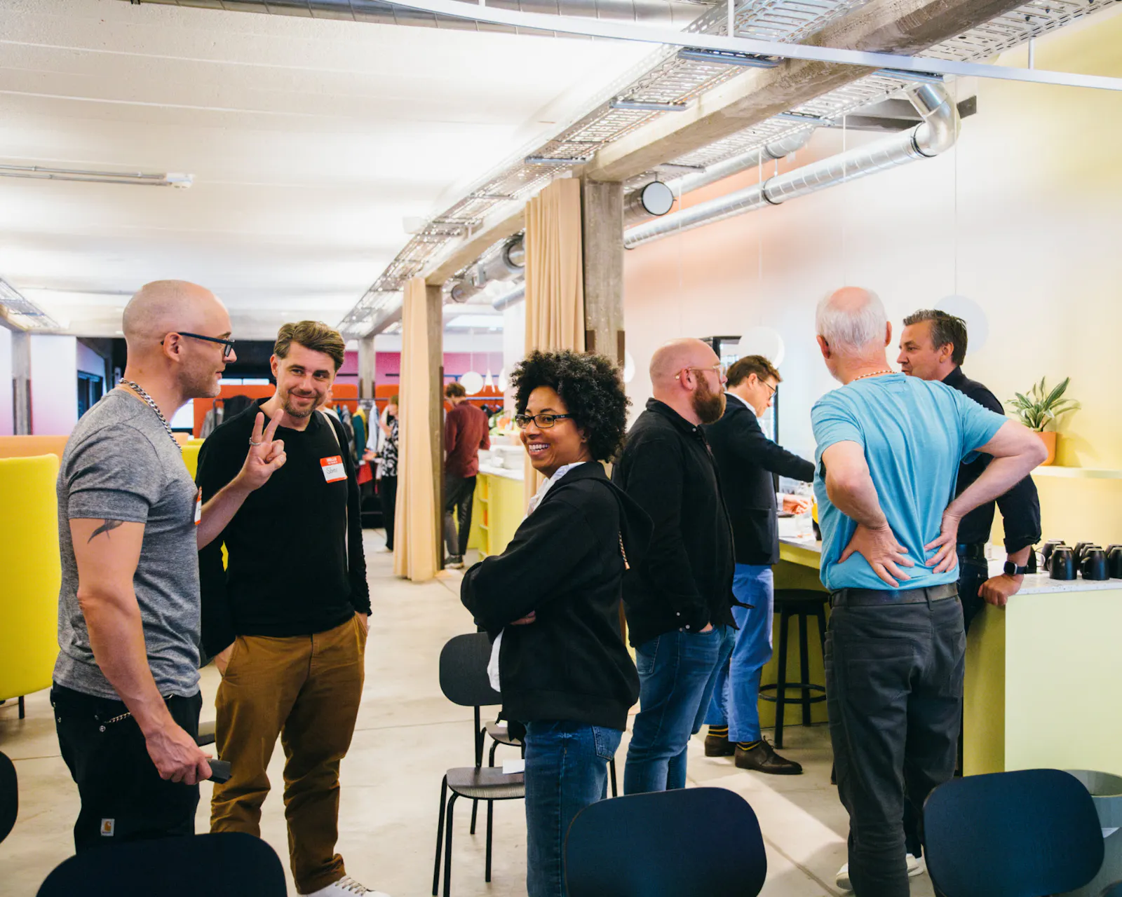 Zwischen den Sessions wird sich ausgetauscht. Eine Gruppe steht im Vordergrund und eine weitere im Hintergrund. Die Stimmung ist gelöst. Alle haben Spass am Austausch.