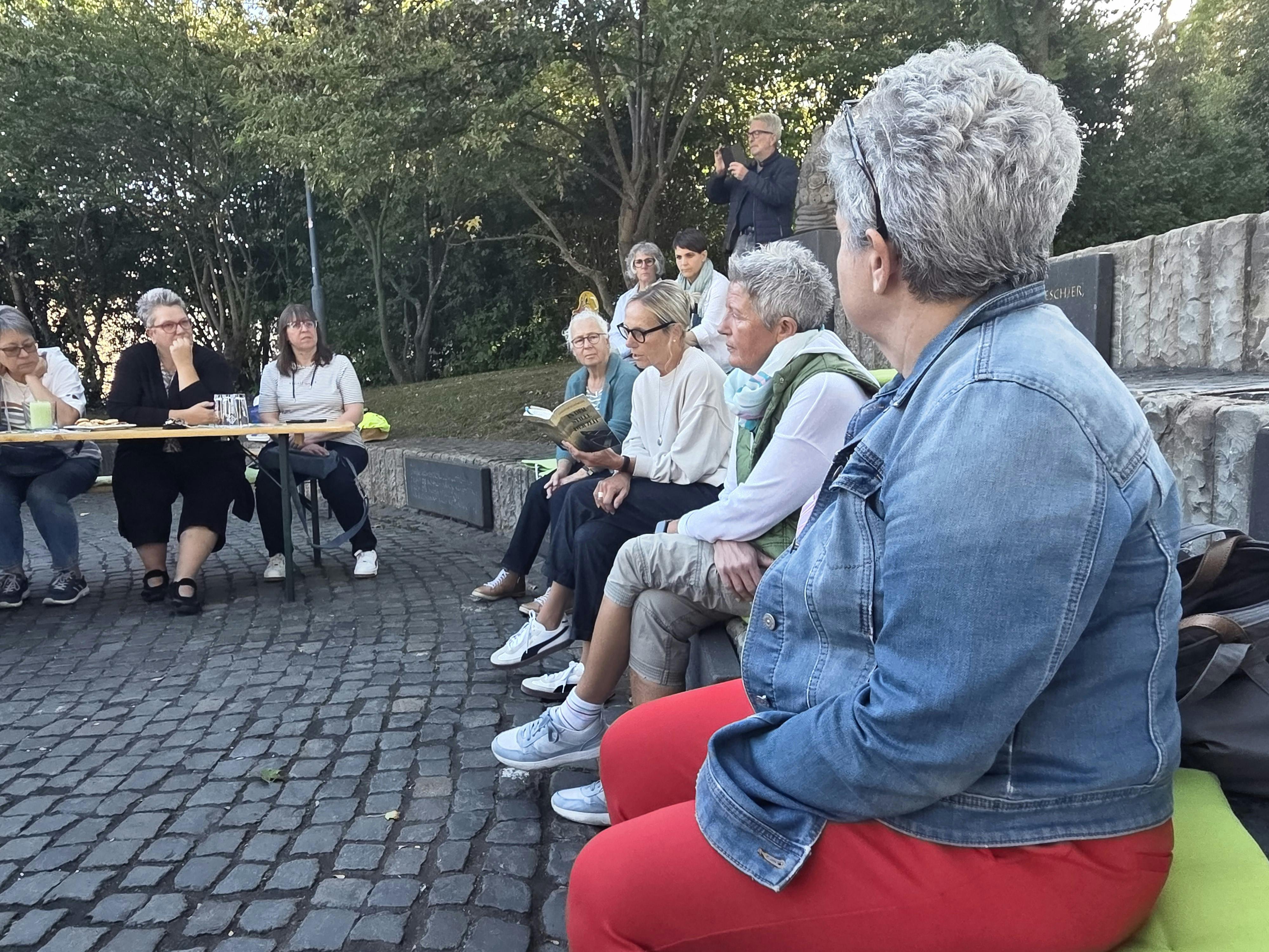 Mehrere Frauen lauschen einer Vorleserin, die aus einem Buch vorliest.