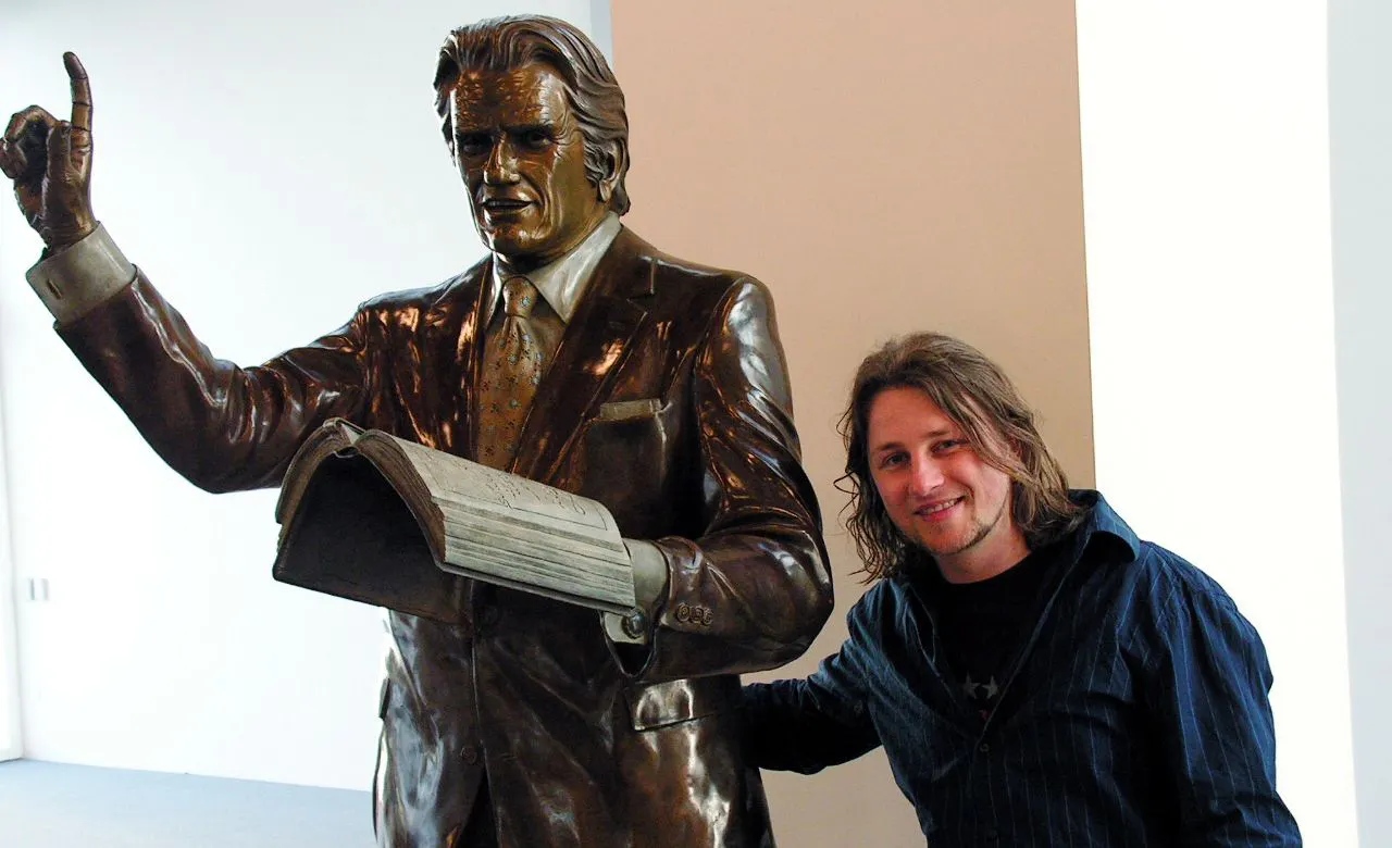 Ein sehr viel jüngerer Gofi steht neben einer Statue des berühmten Evangelisten Billy Graham.