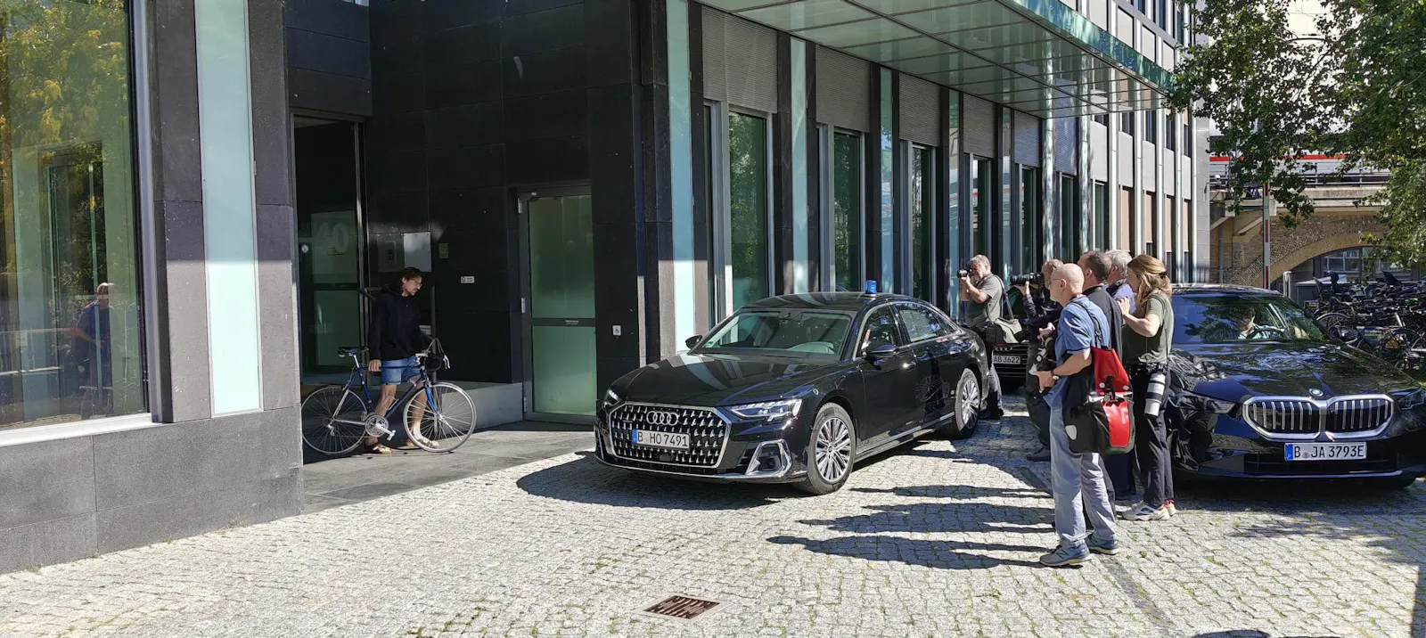 Eine Reihe Fotografen wartet vor der Bundespressekonferenz auf den Innenminister. Ein Radfahrer kommt aus dem Gebäude - und ist es nicht. (c) Falk Steiner 2025