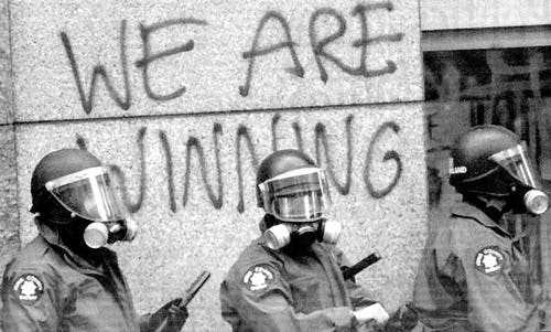 Drei Robocops vor einer Wand, auf der "we are winning" gesprüht wurde.