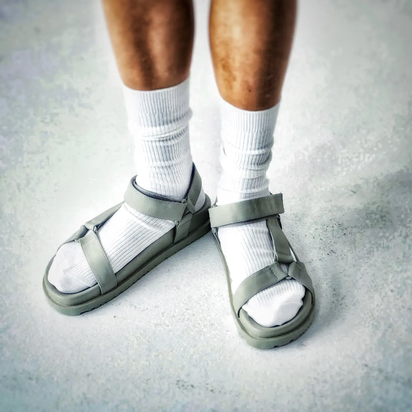 Zwei Füße mit weißen Socken in grauen Sandalen