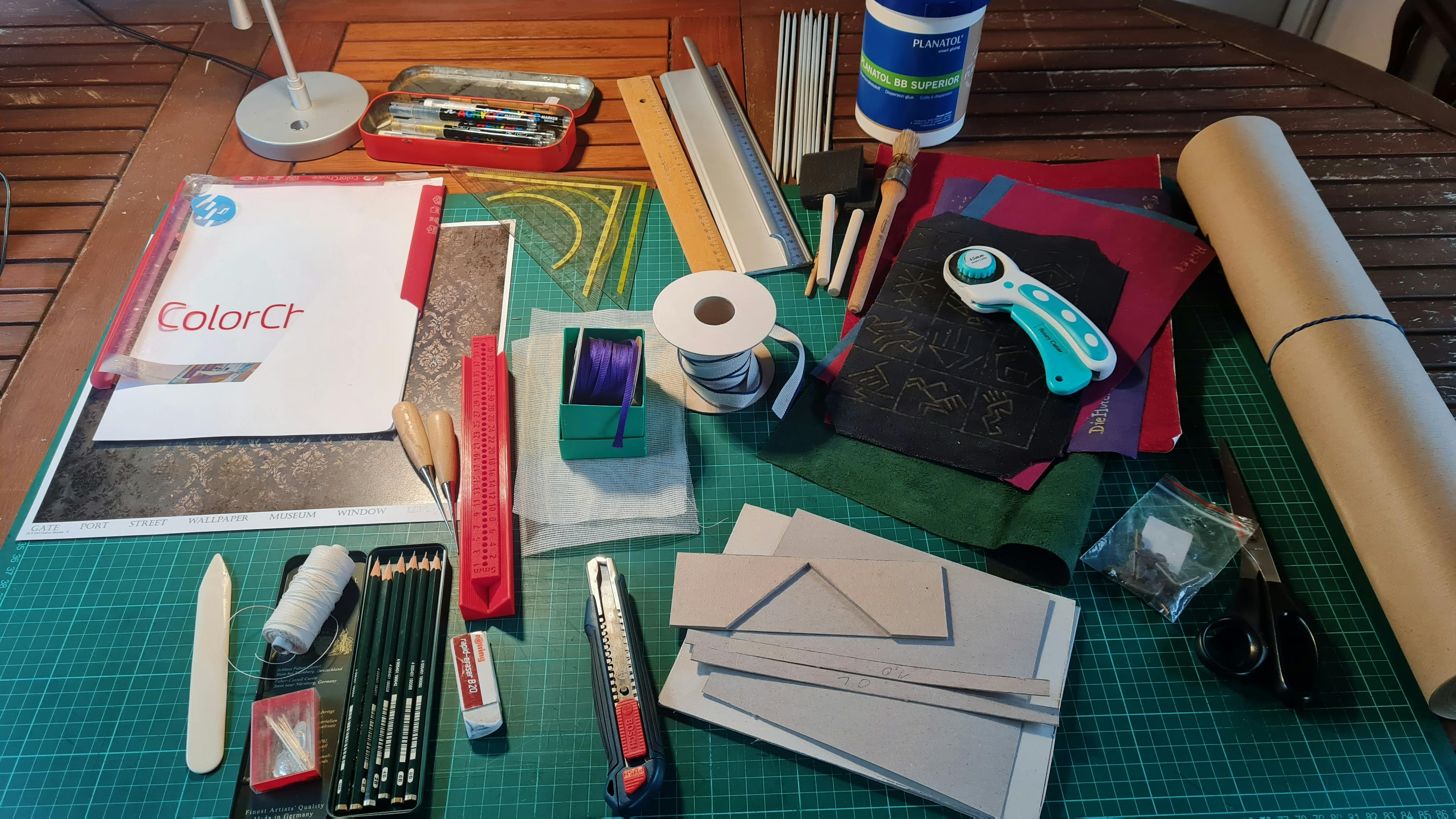 Ein Tisch voll mit Materialien, die man zum Buchbinden benötigt.
