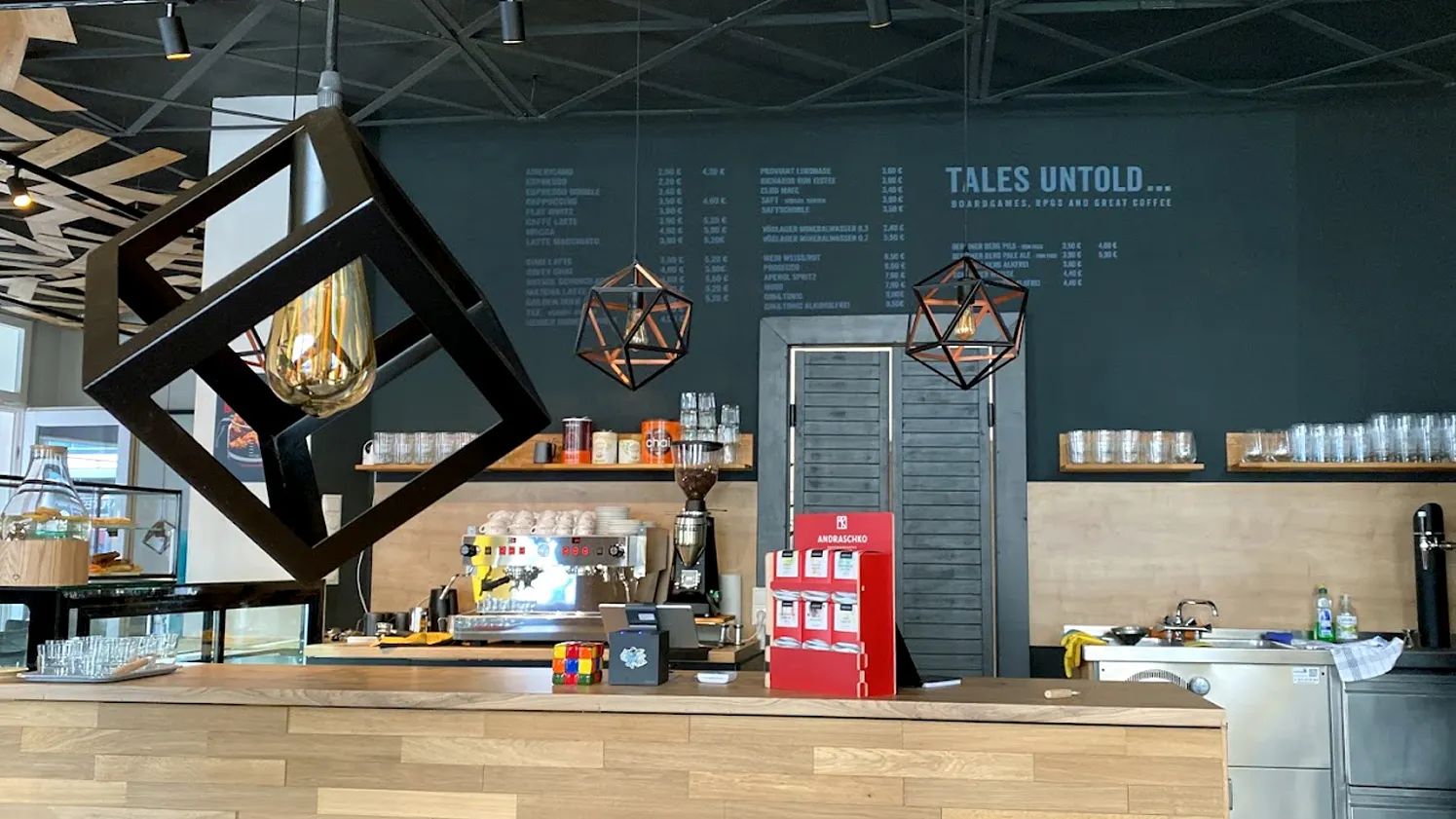 Der Tresen von Tales Untold in warmen Holztönen. Im Hintergrund ist die GetrÀnkekarte auf eine Wandtafel geschrieben.