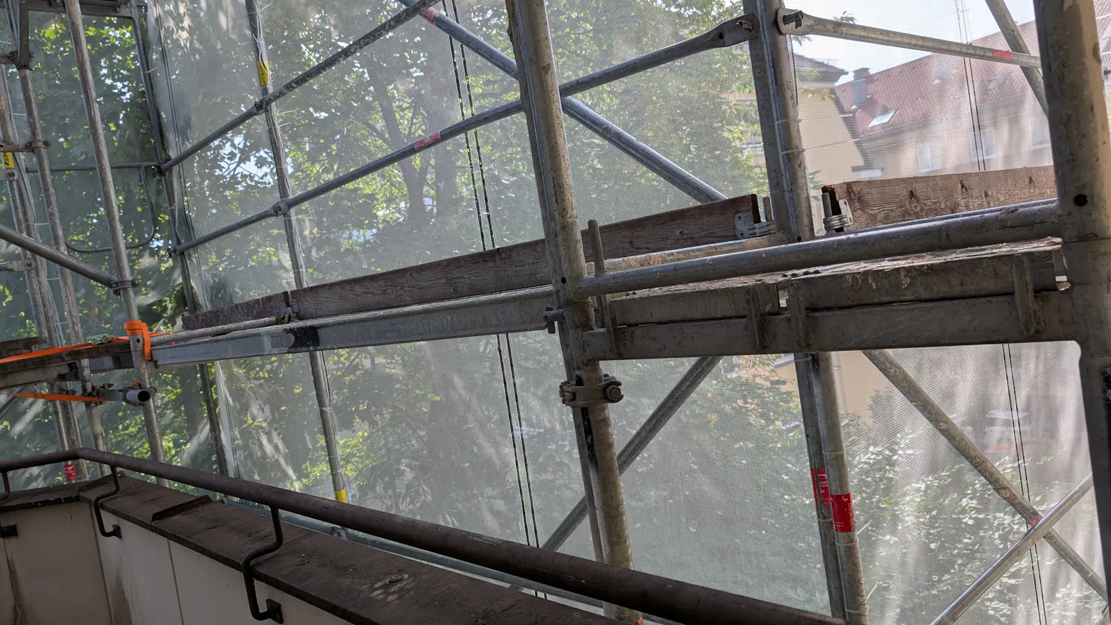 Man sieht ein Baugerüst vor einem Balkon
