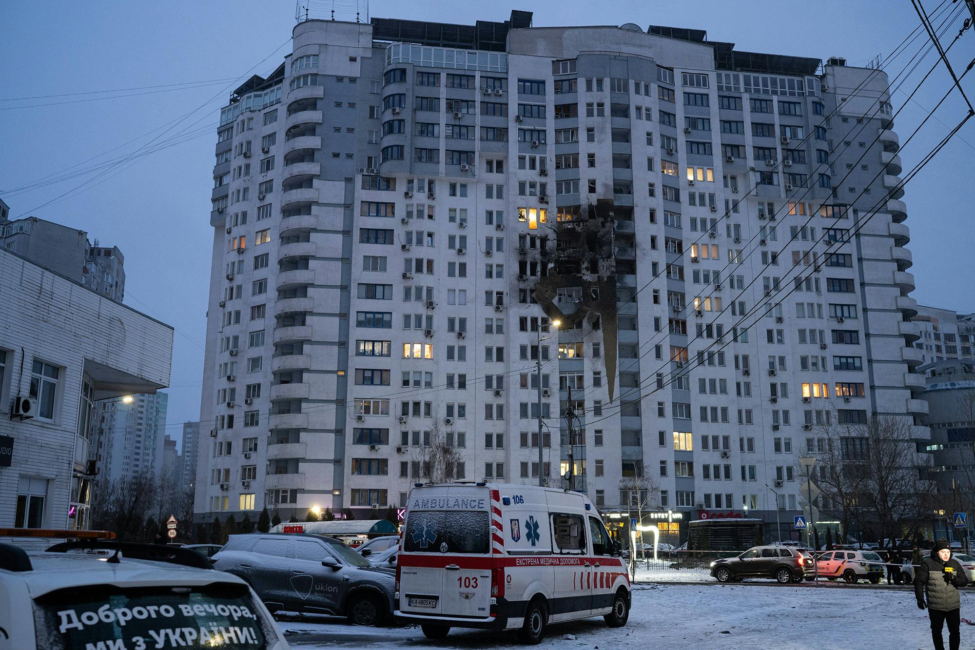 Krankenwagen vor einem großen Wohnblock, in den eine Rakete eingeschlagen ist.