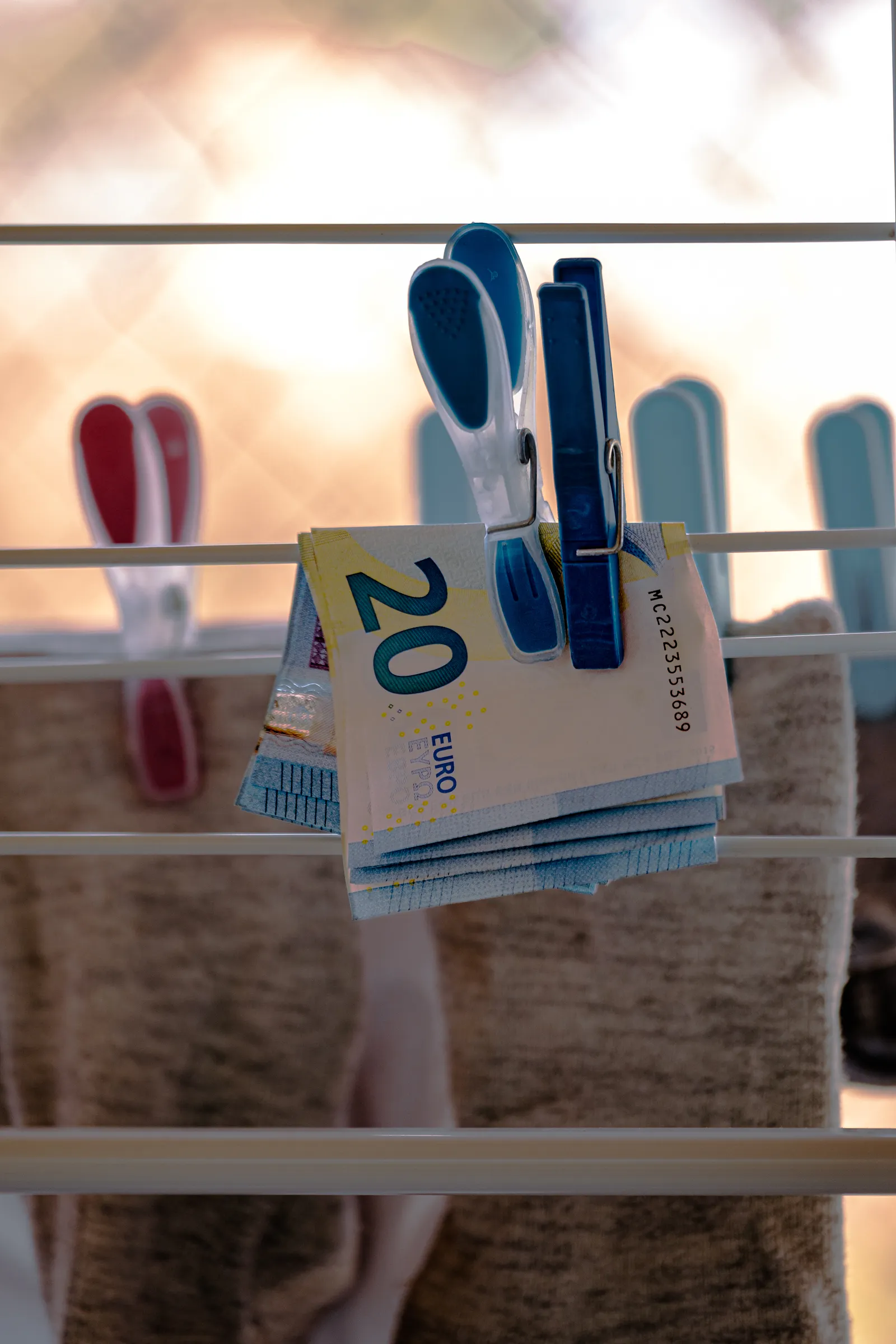 Mehrere 20-Euro-Scheine übereinander auf einem Wäscheständer aufgehängt. Im Hintergrund Socken.