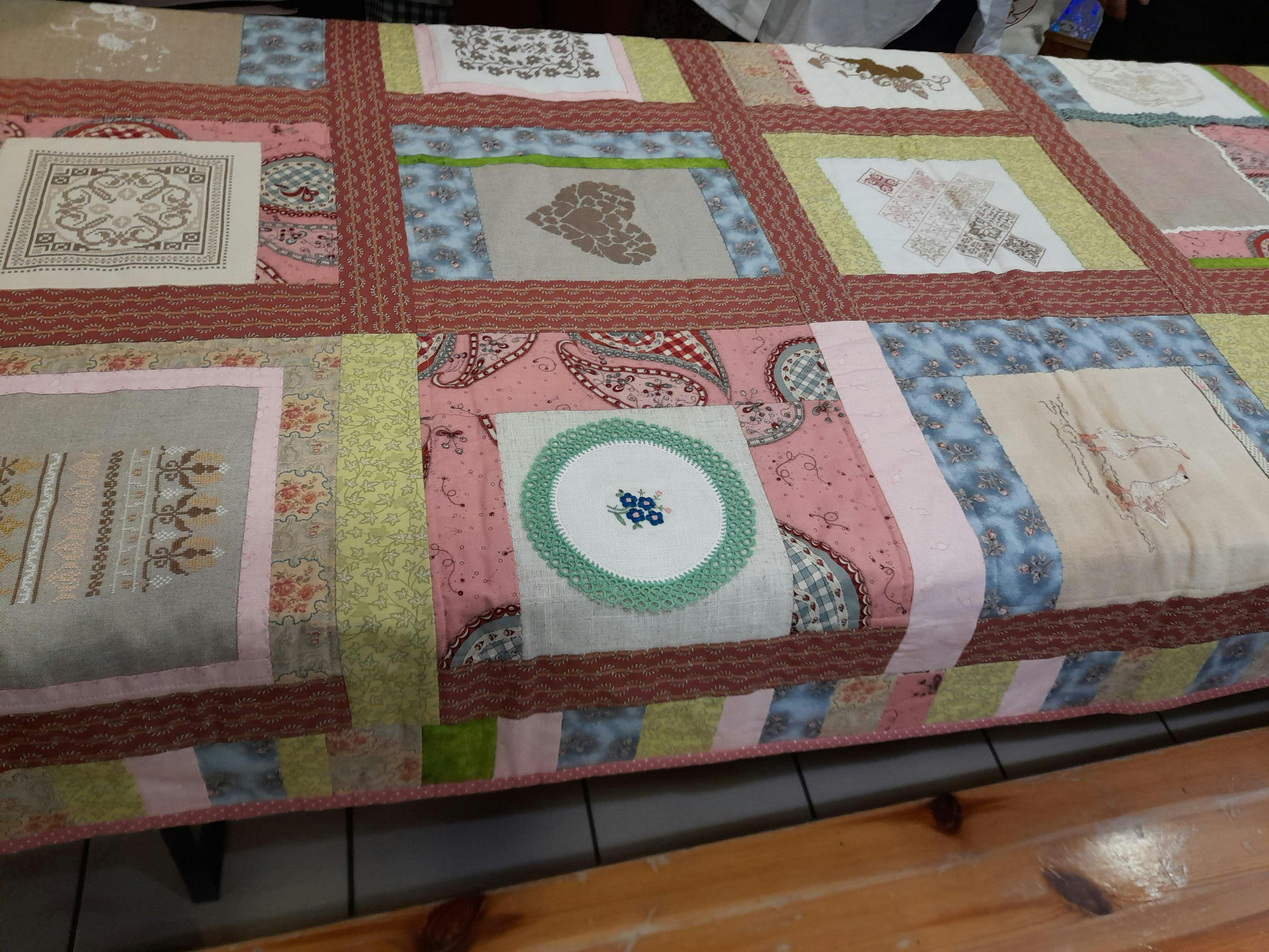 A colourful patchwork blanket with lots of individual embroidery squares.