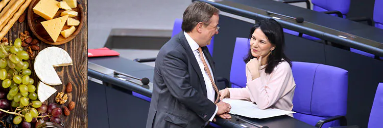 Links im Bild: Eine Käseplatte mit Wein und Trauben.
Rechts im Bild: Armin Laschet und Annalena Baerbock im Bundestag. Sie lächeln und führen ein freundliches Gespräch.