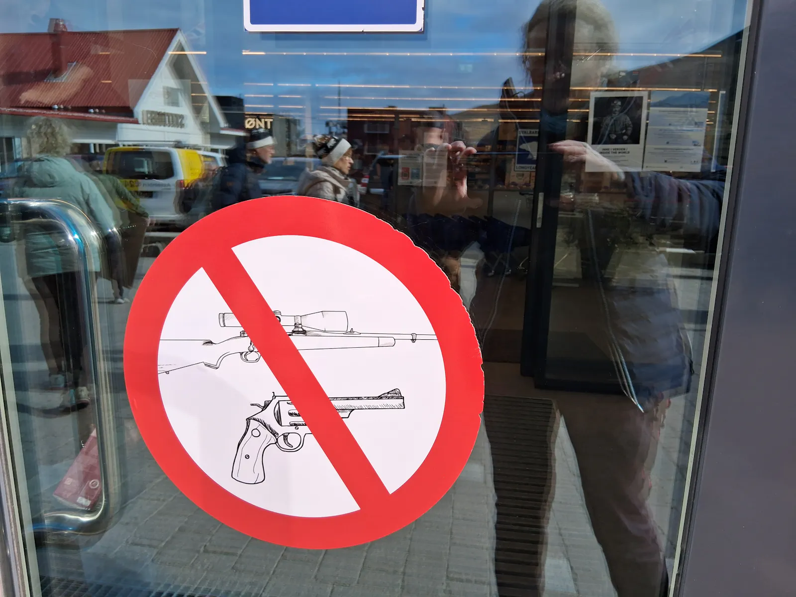 Schild mit durchgestricheren Waffen an Glastür