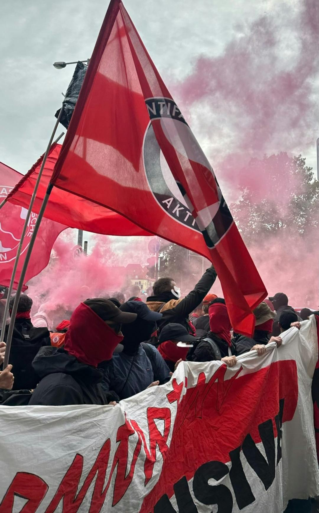 Foto aus Erfurt, rote Antifa-Flagge, Menschen mit Transparent, Rauch