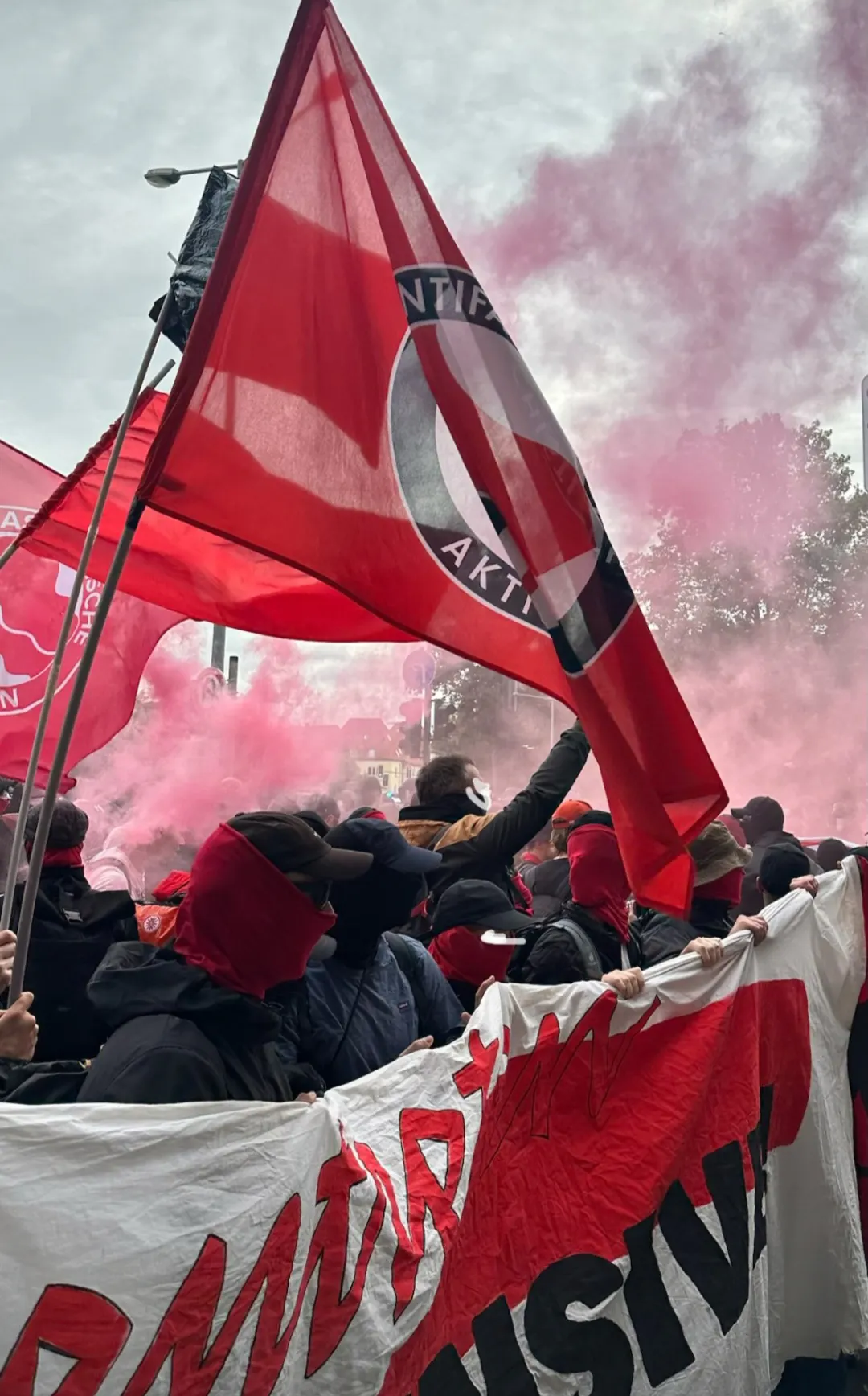 Foto aus Erfurt, rote Antifa-Flagge, Menschen mit Transparent, Rauch