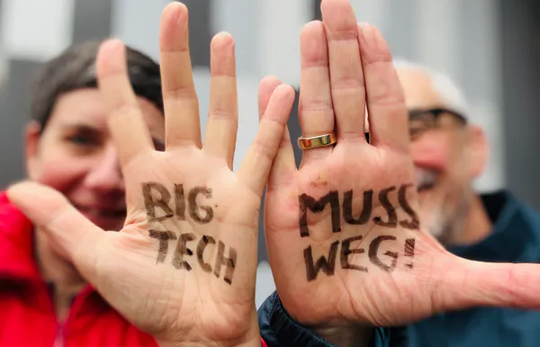 Ilona und Marek zeigen ihre Hände, auf denen "BIG TECH MUSS WEG!" steht.
