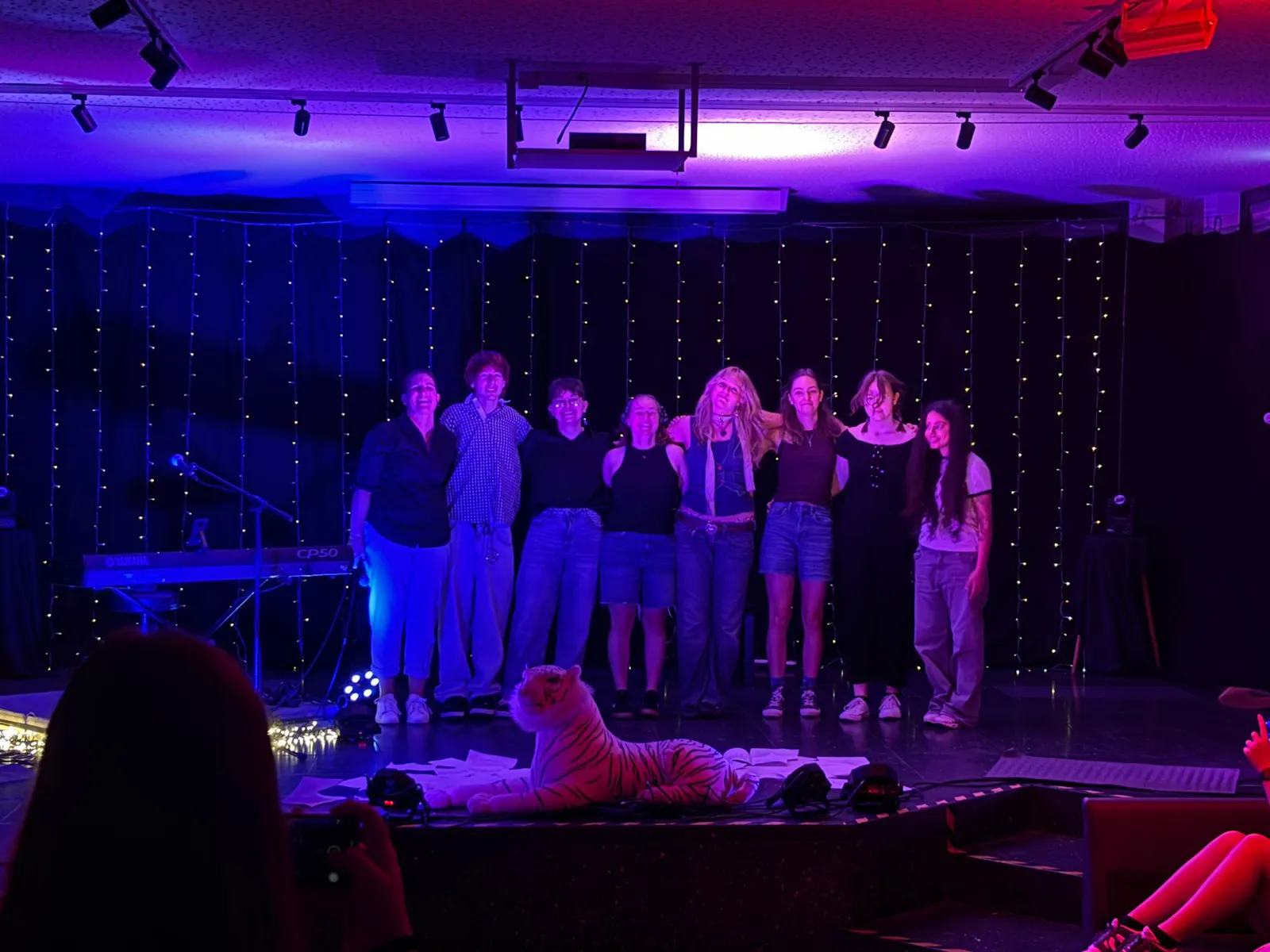 Auf dem Bild stehen acht Menschen auf einer Bühne nach erfolgreichem Auftritt