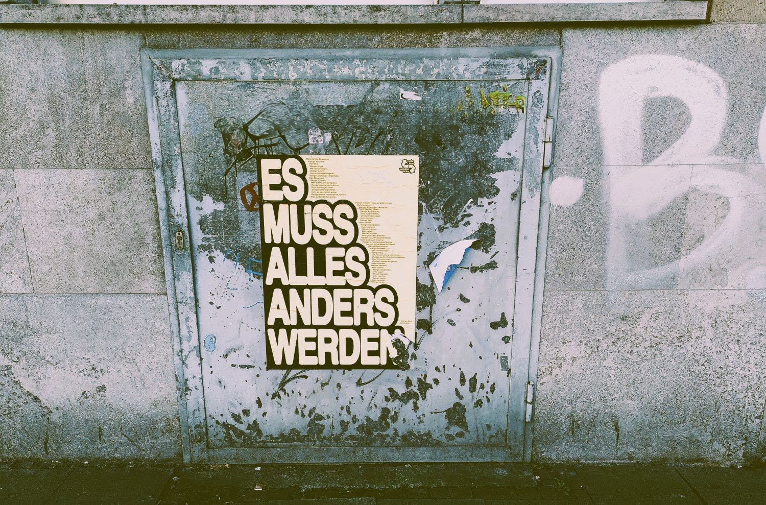 Ein Plakat hängt an einer Wand, darauf steht: Es muss alles anders werden