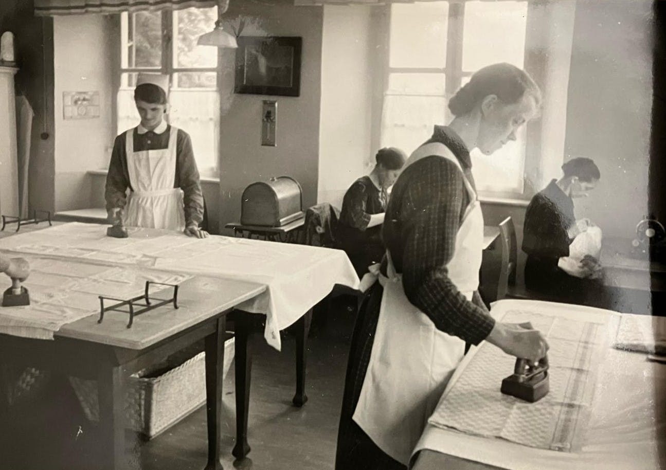 Arbeitsalltag im Wanderhof. Das Bild aus dem Archiv Herzogsägmühle zeigt vier Frauen beim Bügel von Wäsche.