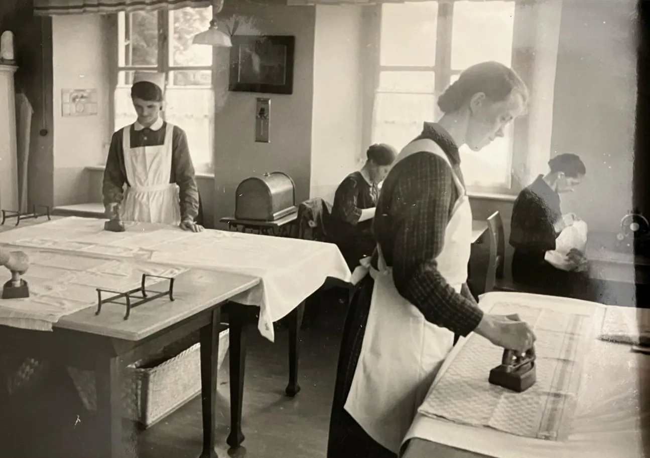 Arbeitsalltag im Wanderhof. Das Bild aus dem Archiv Herzogsägmühle zeigt vier Frauen beim Bügel von Wäsche.