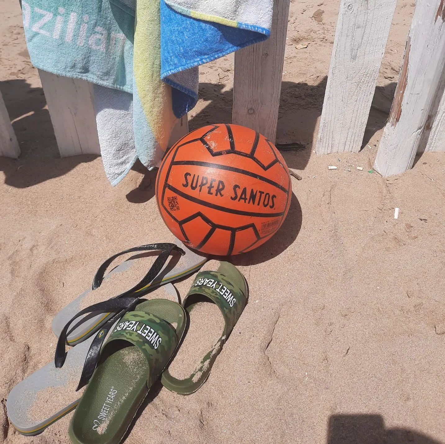 Ein Super-Santos-Ball an einem italienischen Strand im Sommer, umgeben von aufgehängten Strandtüchern und Strandsandalen