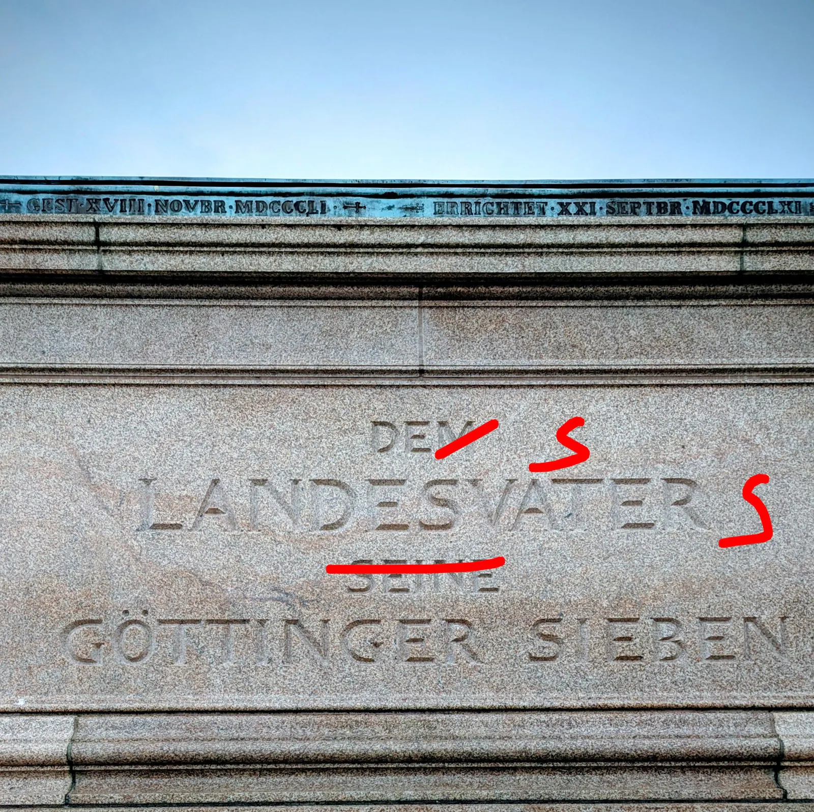 Ein Monument am Göttinger Bahnhof, auf dem geschrieben steht: Dem Landesvater seine Göttinger Sieben. Ich habe es mit Rotstift korrigiert: Des Landesvaters Göttinger Sieben.