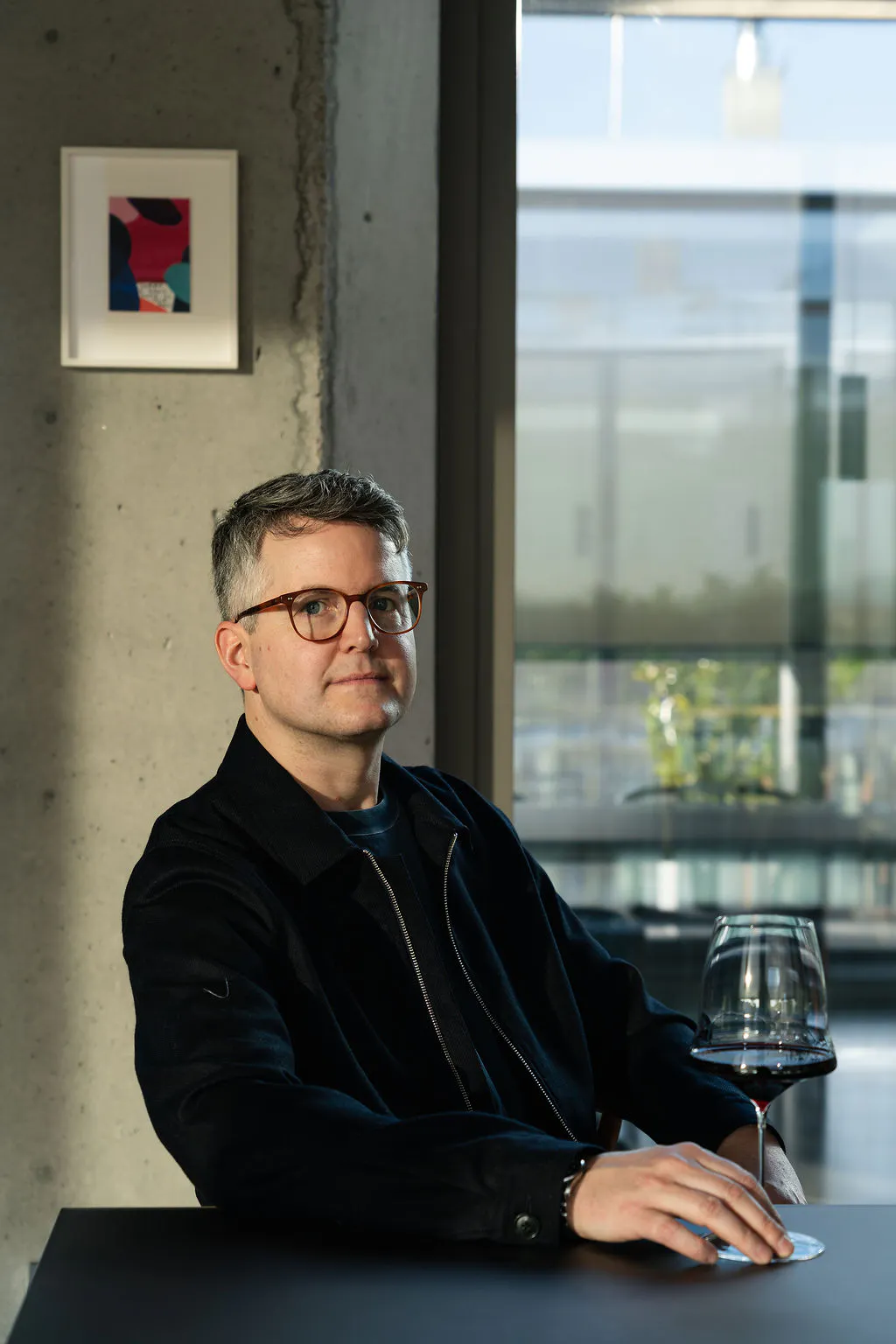 Ein Mann sitzt an einem Tisch. Vor ihm steht ein Weinglas mit Rotwein